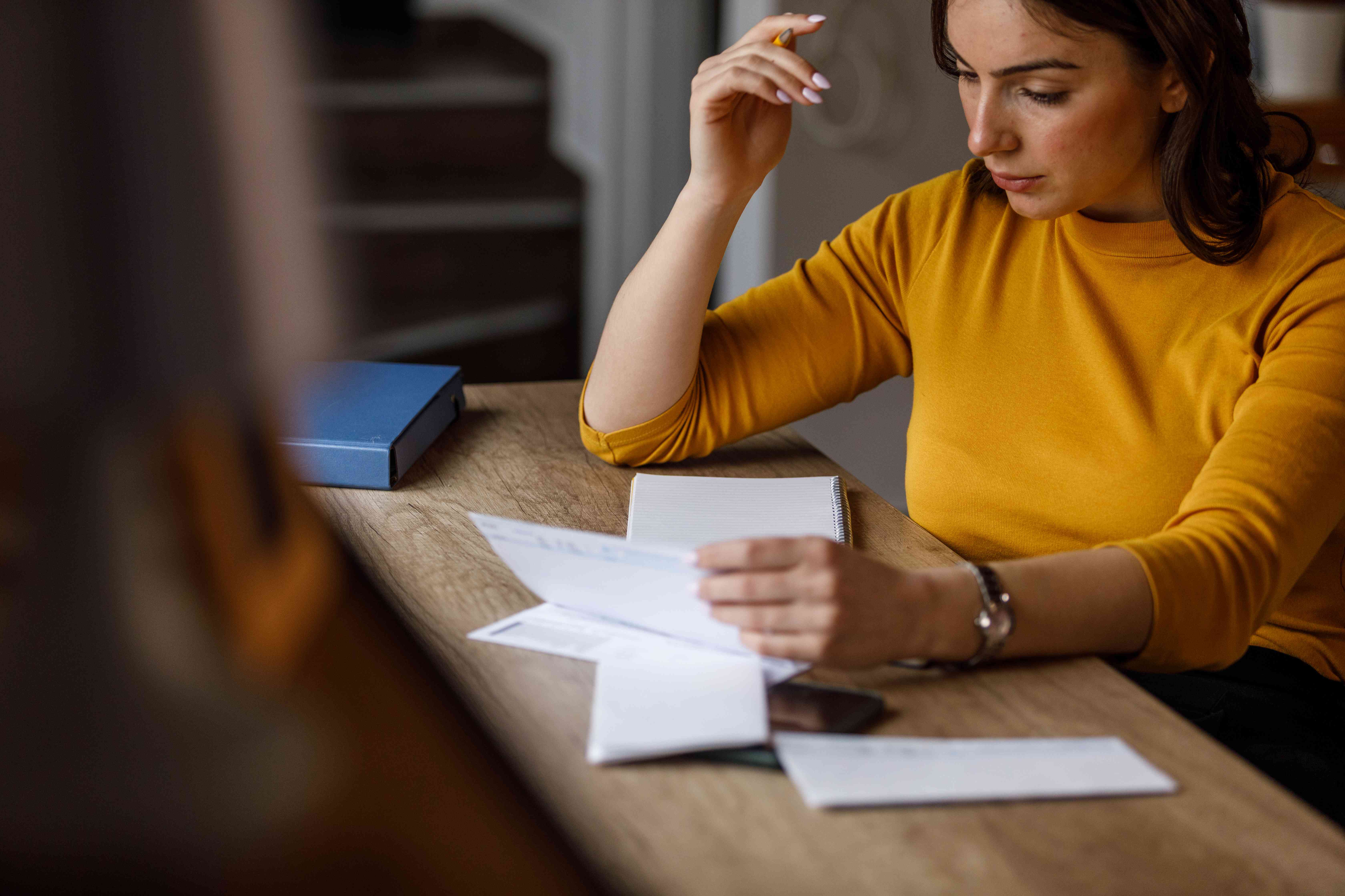 Worried young woman sitting at her desk stressing about a check being hold