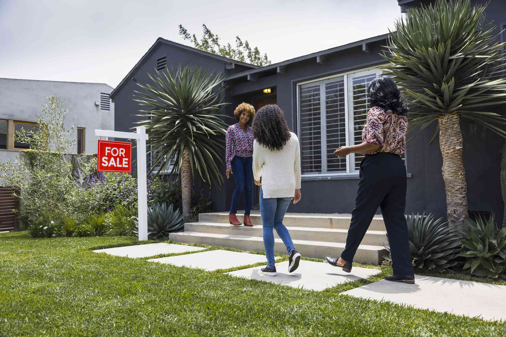 Saleswoman greeting female customers while standing outside house