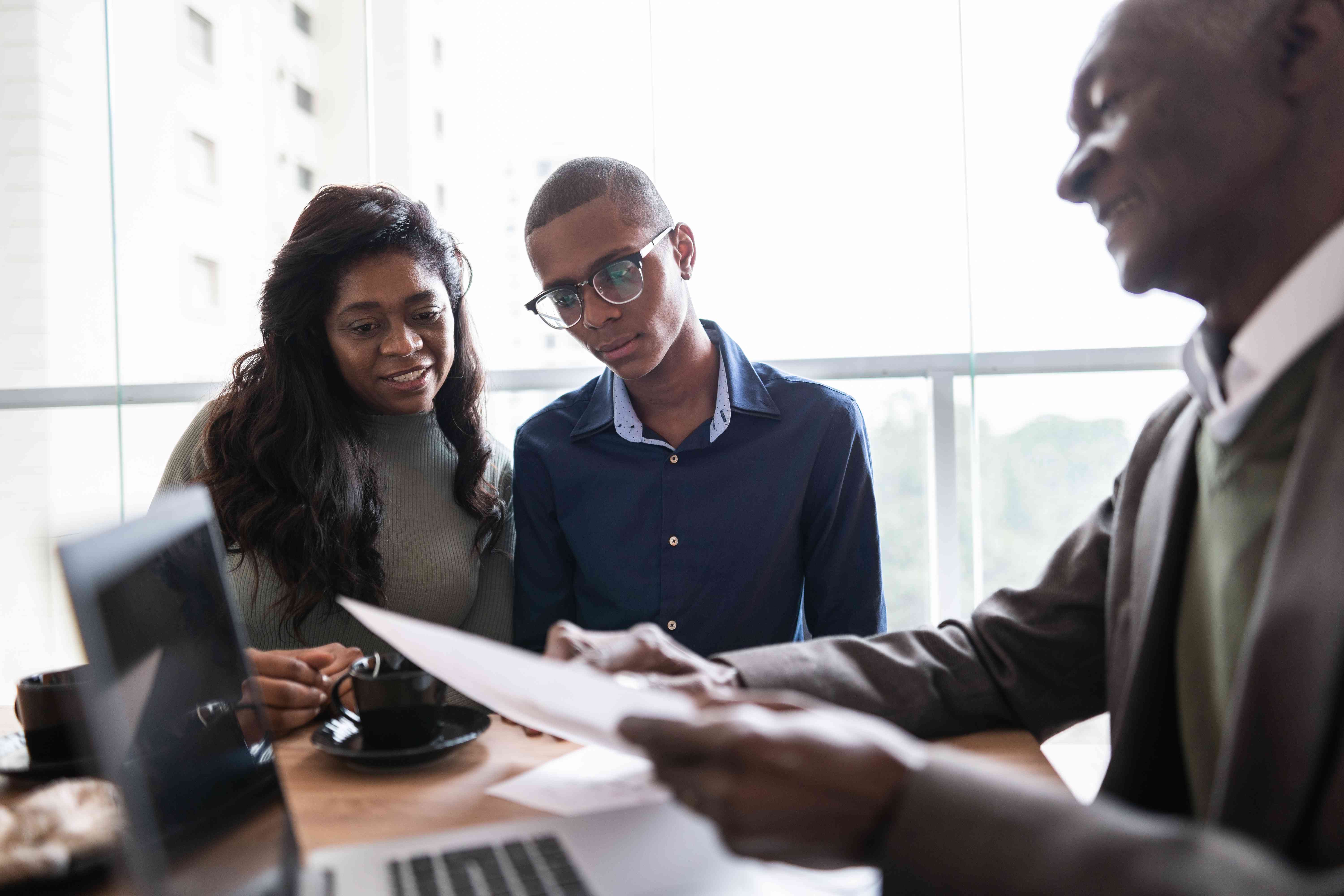 Investment advisor in an office giving two potential investors information about bond funds.