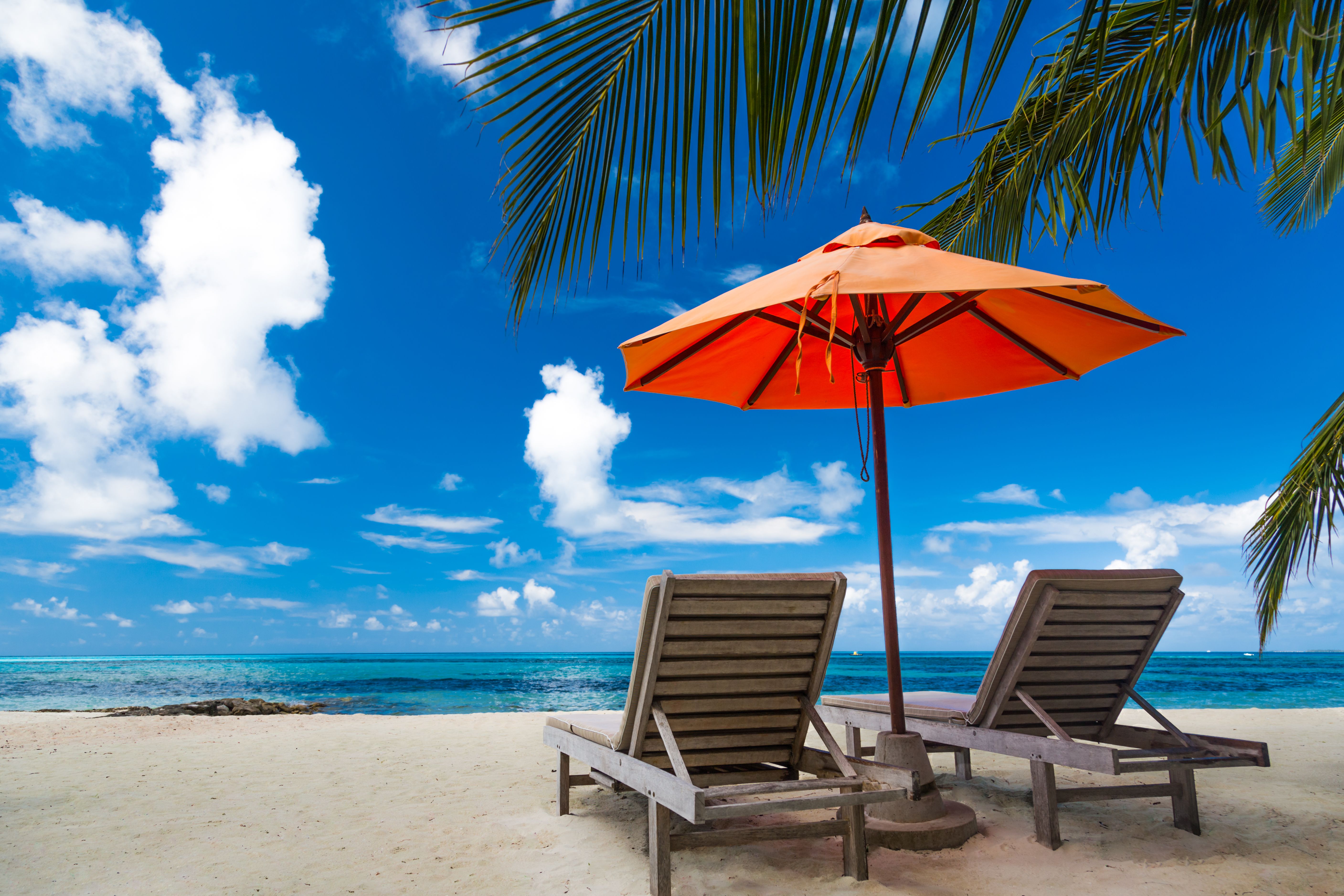 Beautiful beach background for summer travel with sun,coconut tree and beach wooden bed on sand with beautiful blue sea and blue sky. Summer mood sun beach background concept.