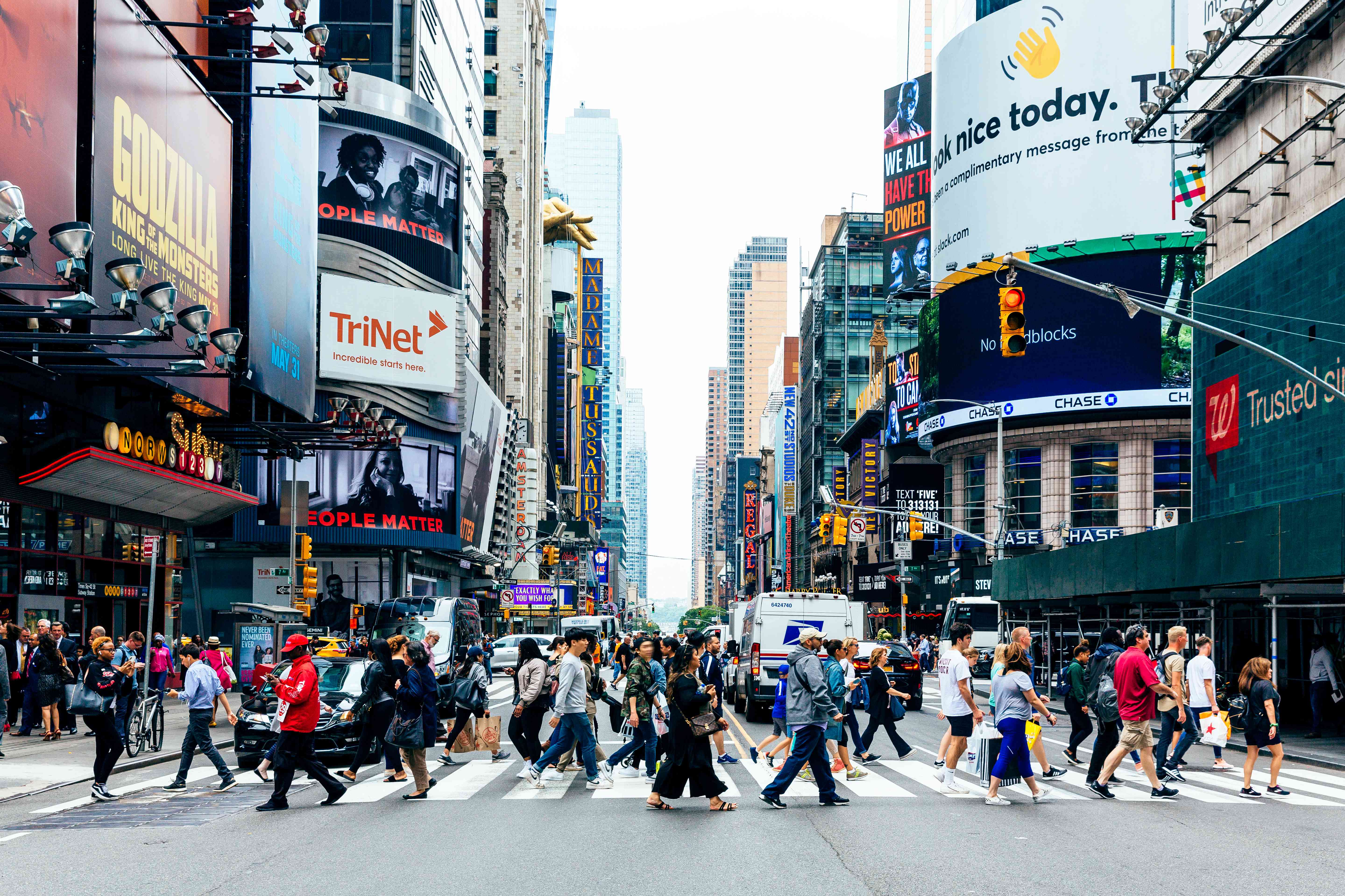 A crowd crossing at a busy crosswalk in Times Square