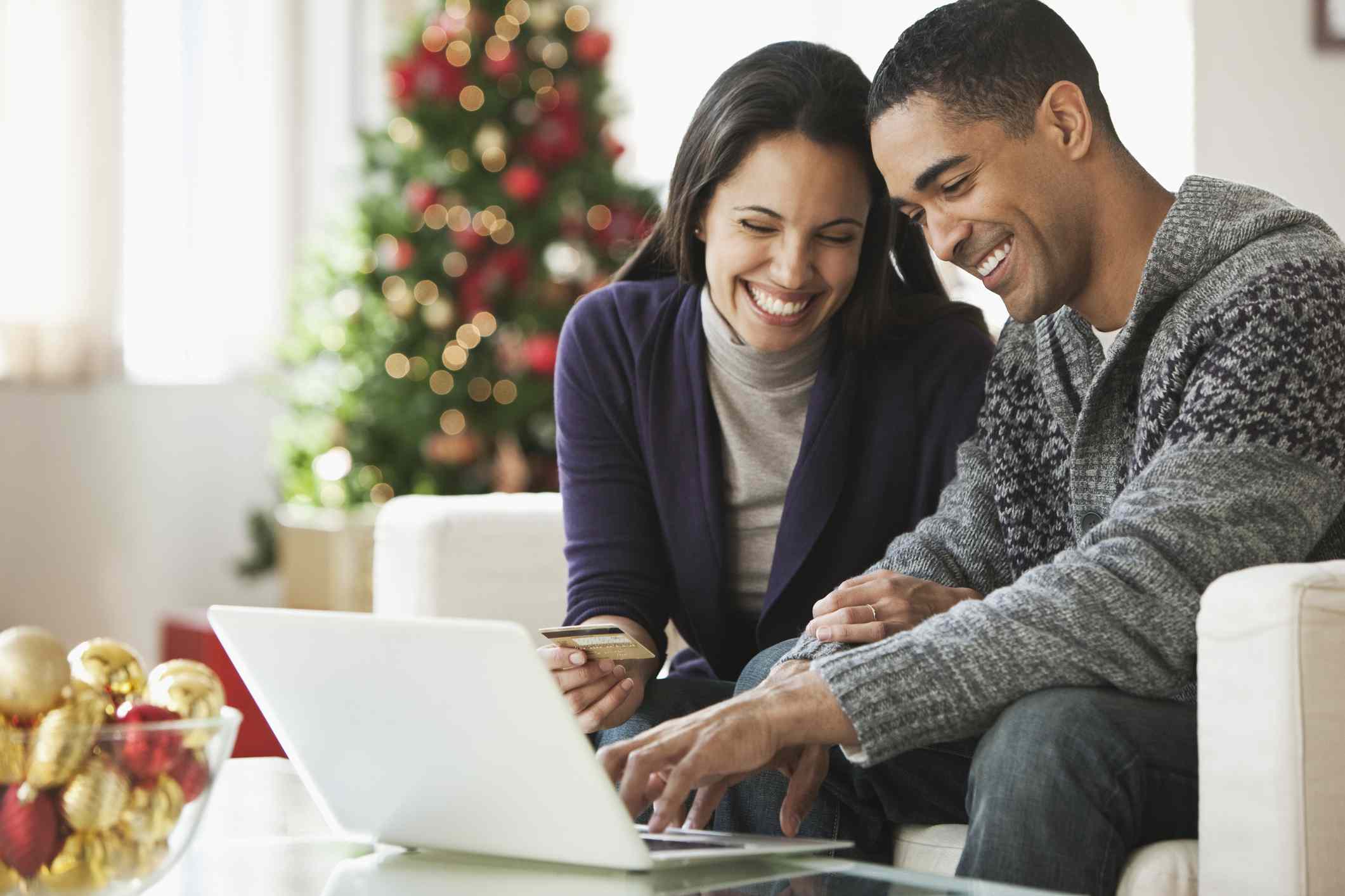 Couple holding credit card and using laptop.