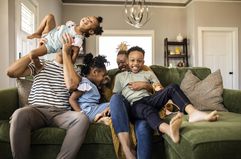 Family of five playing together on a sofa at home