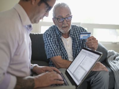 Son using a laptop to review his father's credit card bill showing several recurring payments.