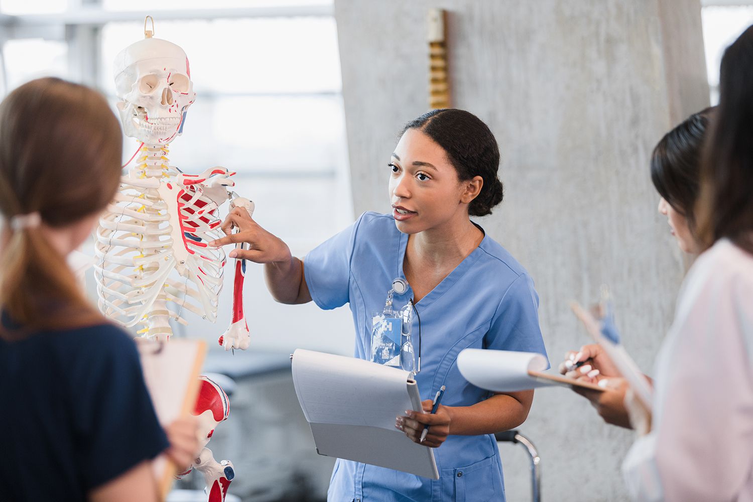 Young woman teaches class on human bone structure medical school