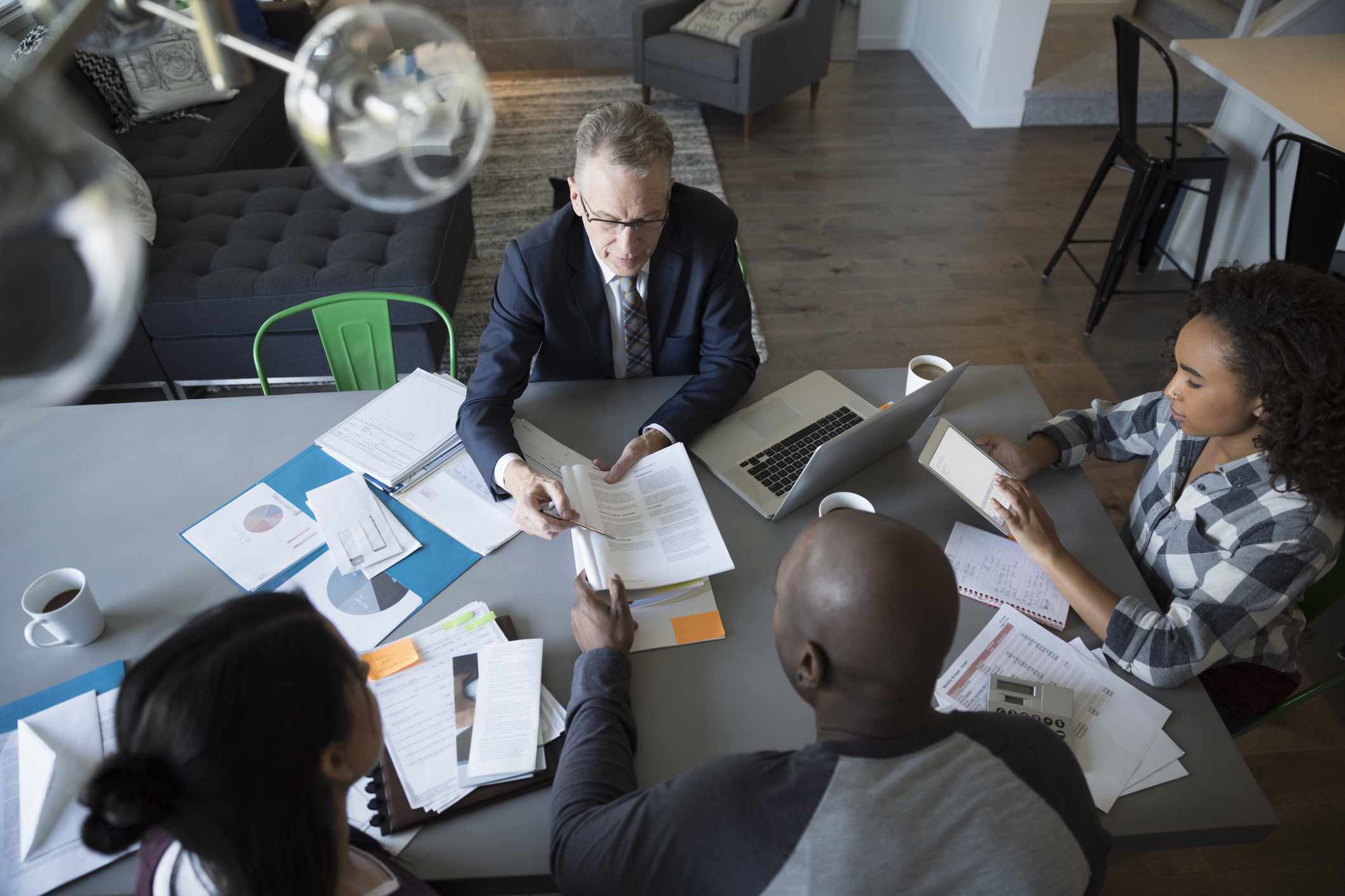 Financial advisor with laptop and paperwork meeting with family at dining room table