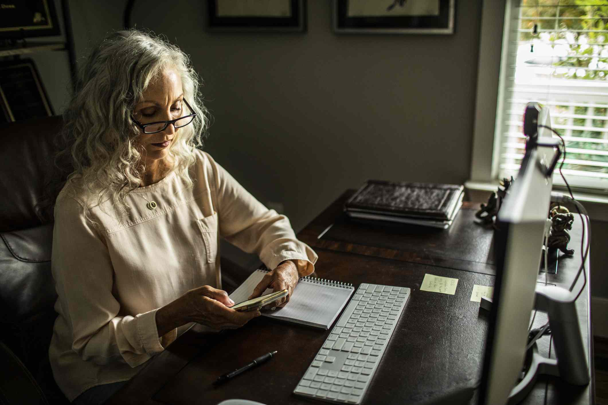 A woman uses a calculator at a desk.