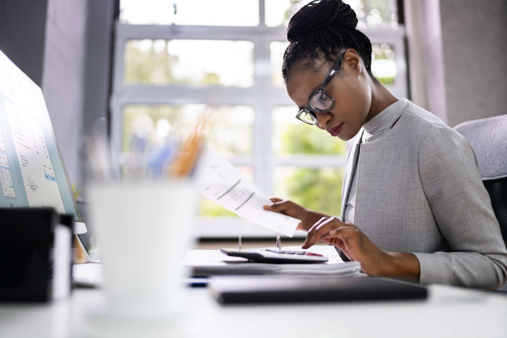 A woman uses a calculator at a desk. 