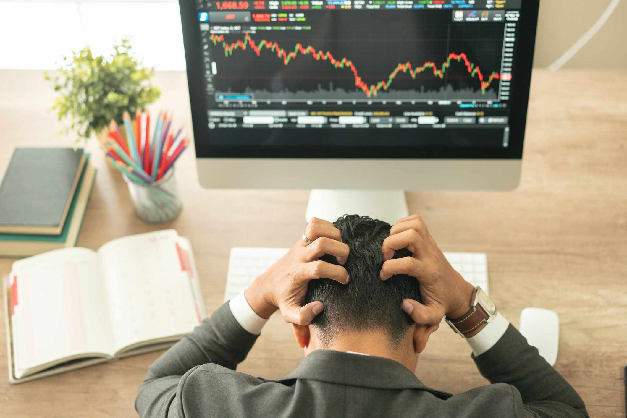 Businessman grabs head with business chart on screen