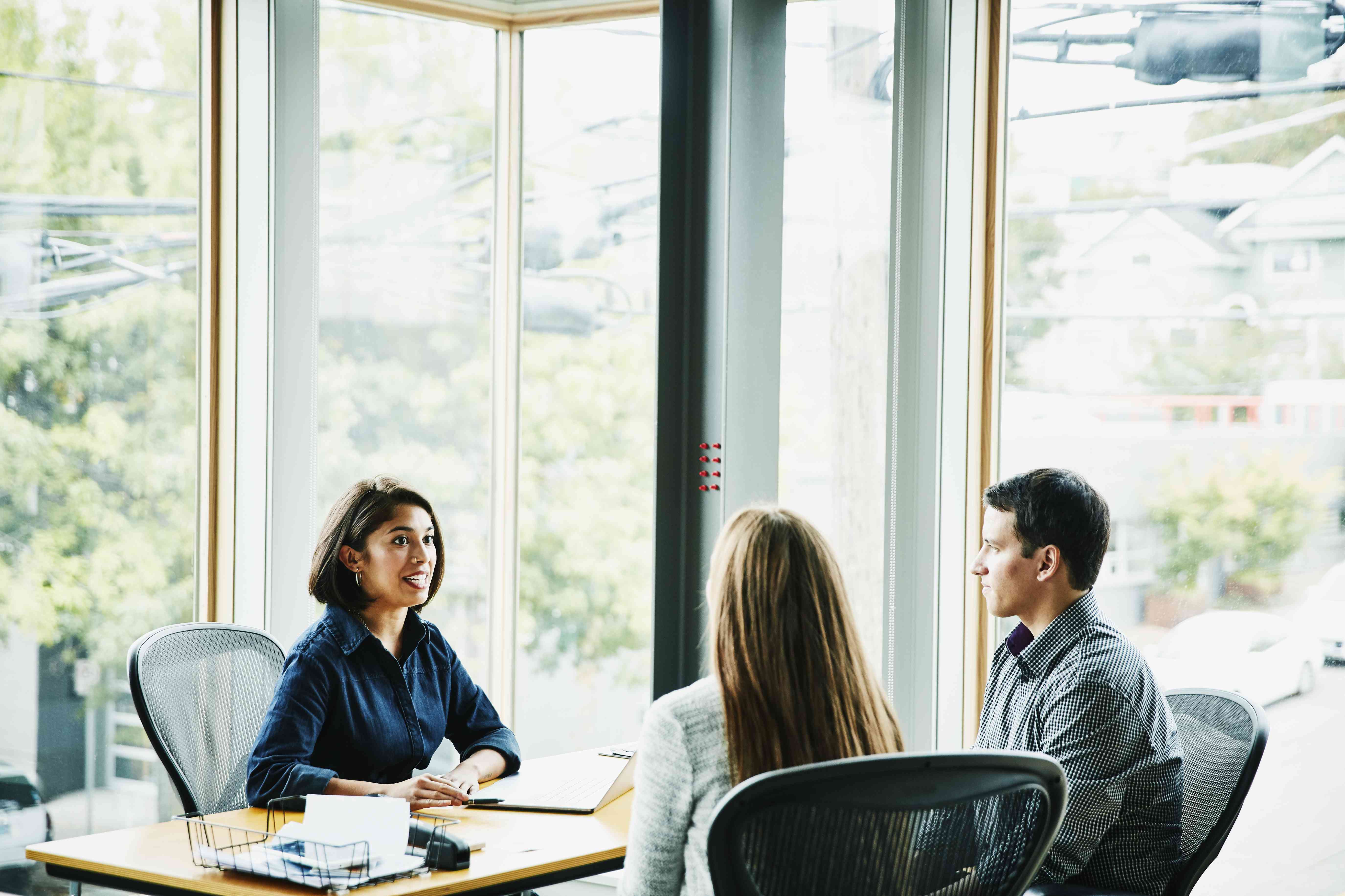 Smiling businesswoman in discussion with clients at office workstation