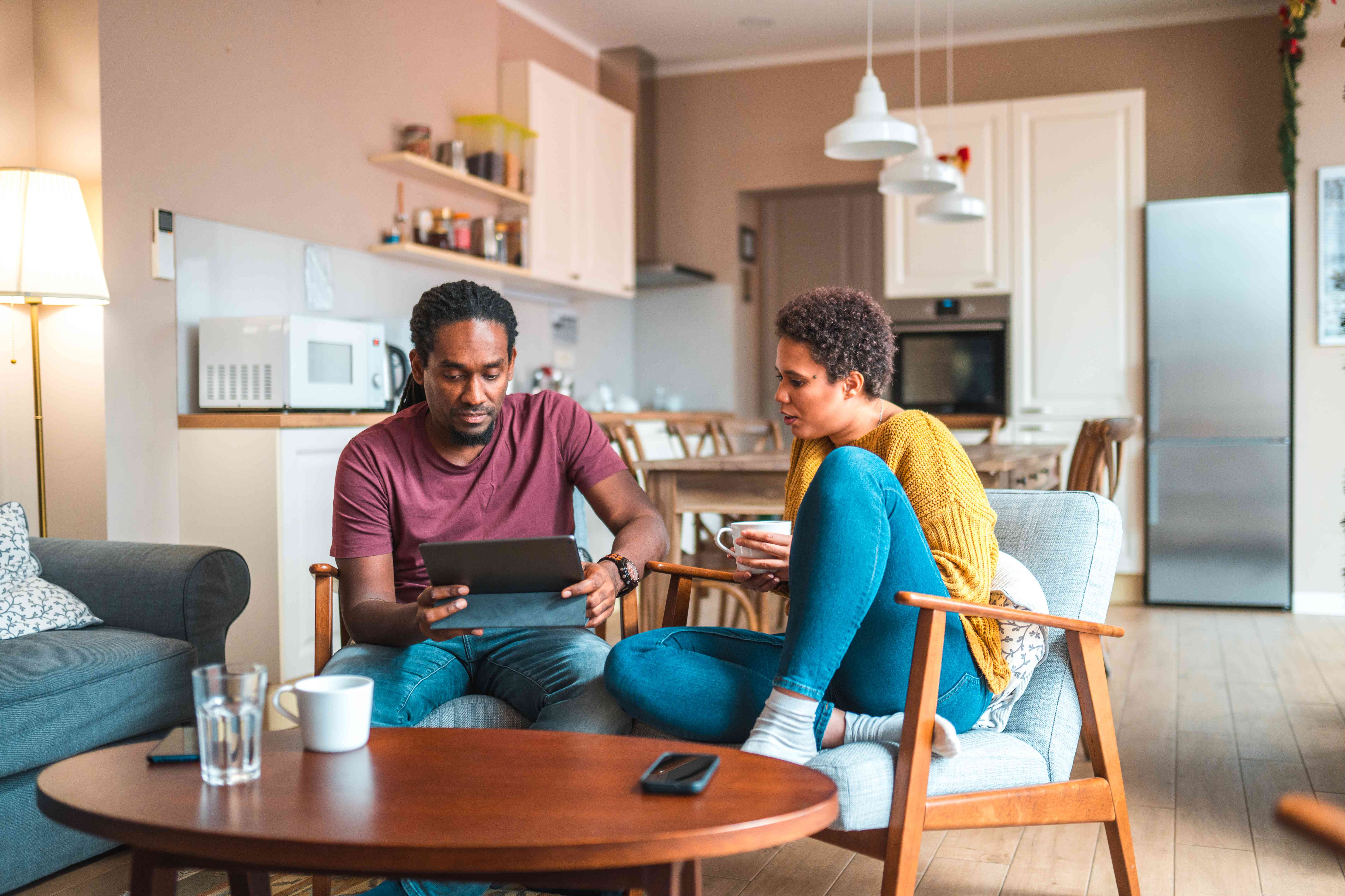 Couple hanging out and checking out mortgage rates on tablet while having coffee