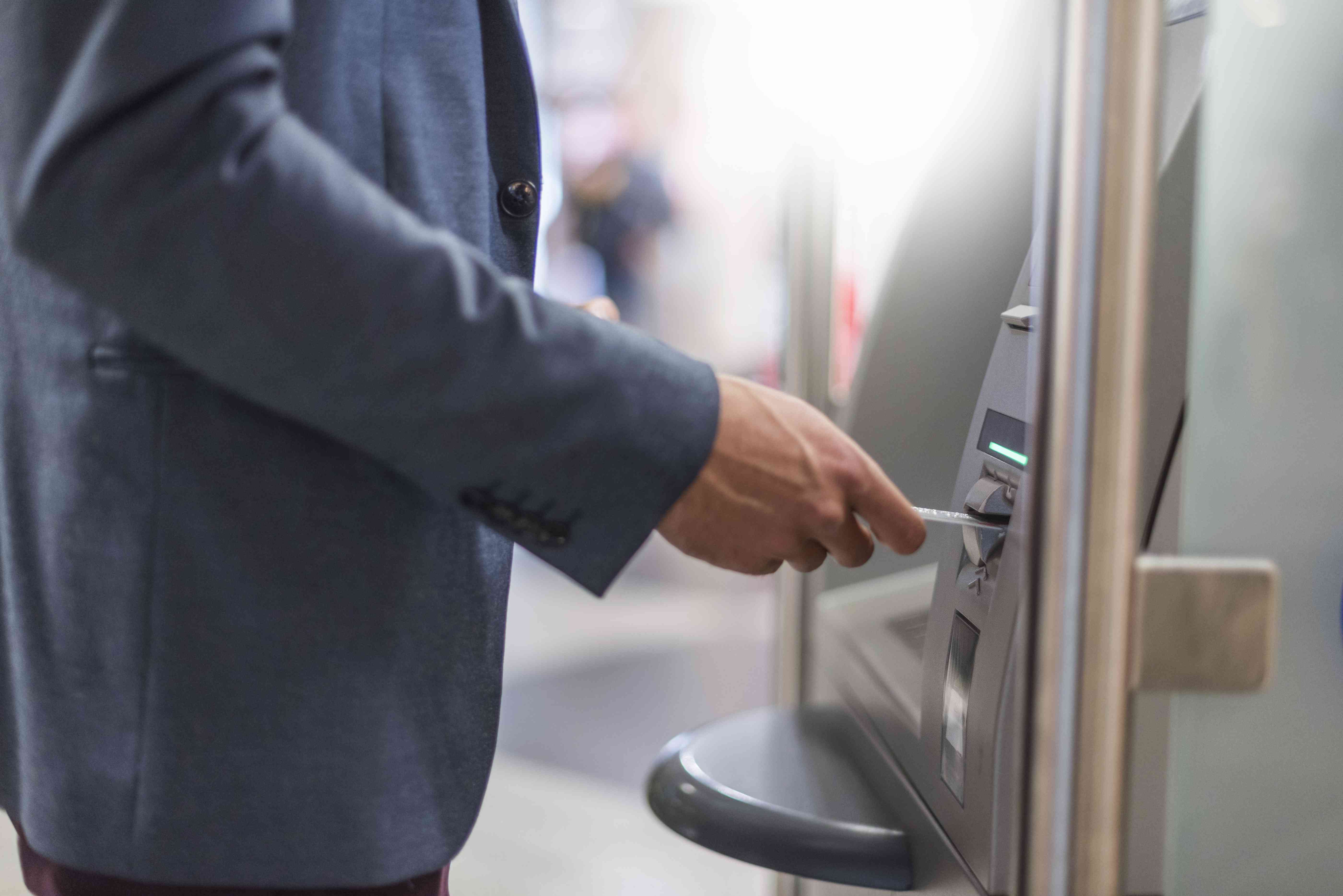 Close-up of businessman withdrawing money at an ATM