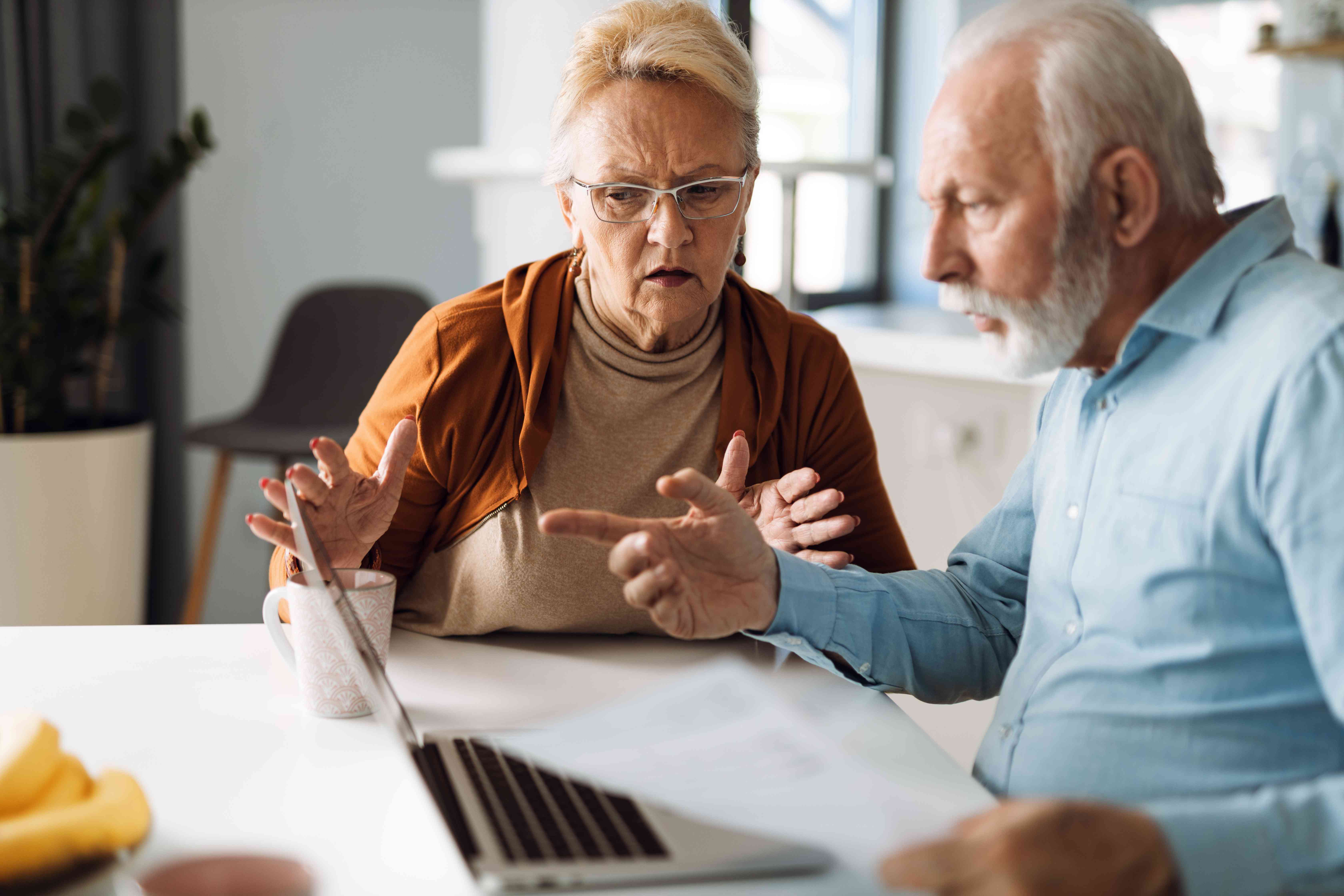 Frustrated senior couple sitting at home checking their finances