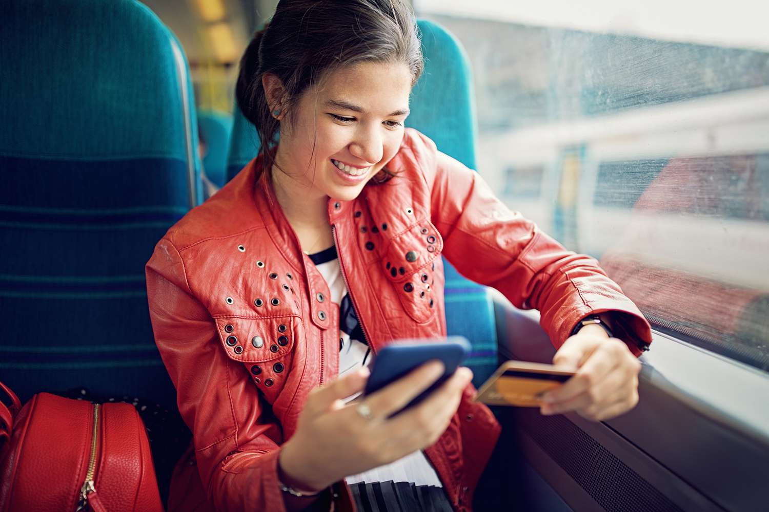 Young teenage girl is shopping online/making reservation in the train