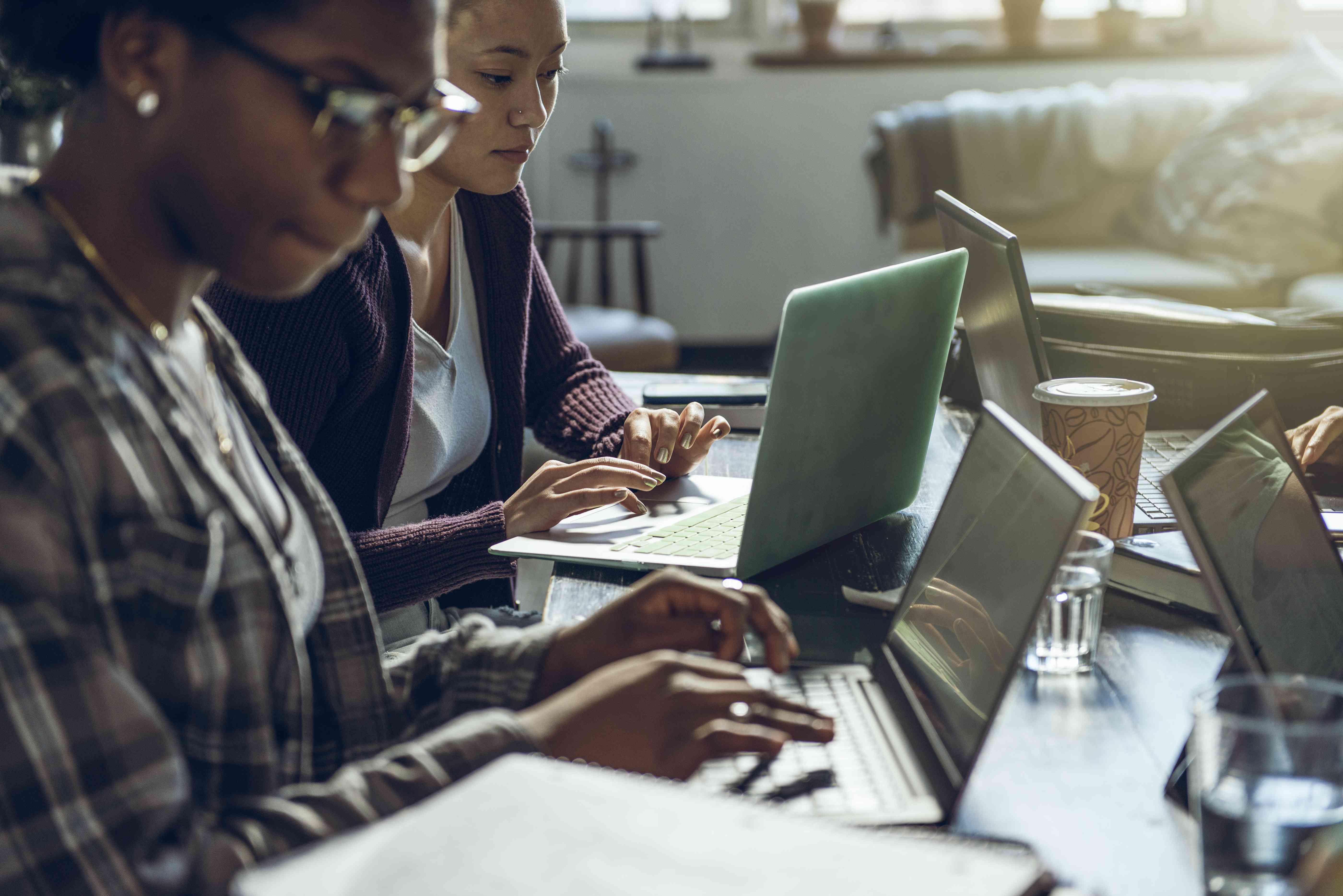 College students study around a table with laptops. 