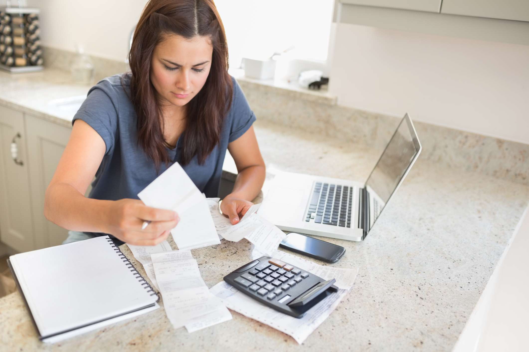 Young woman works on finances with laptop and calculator