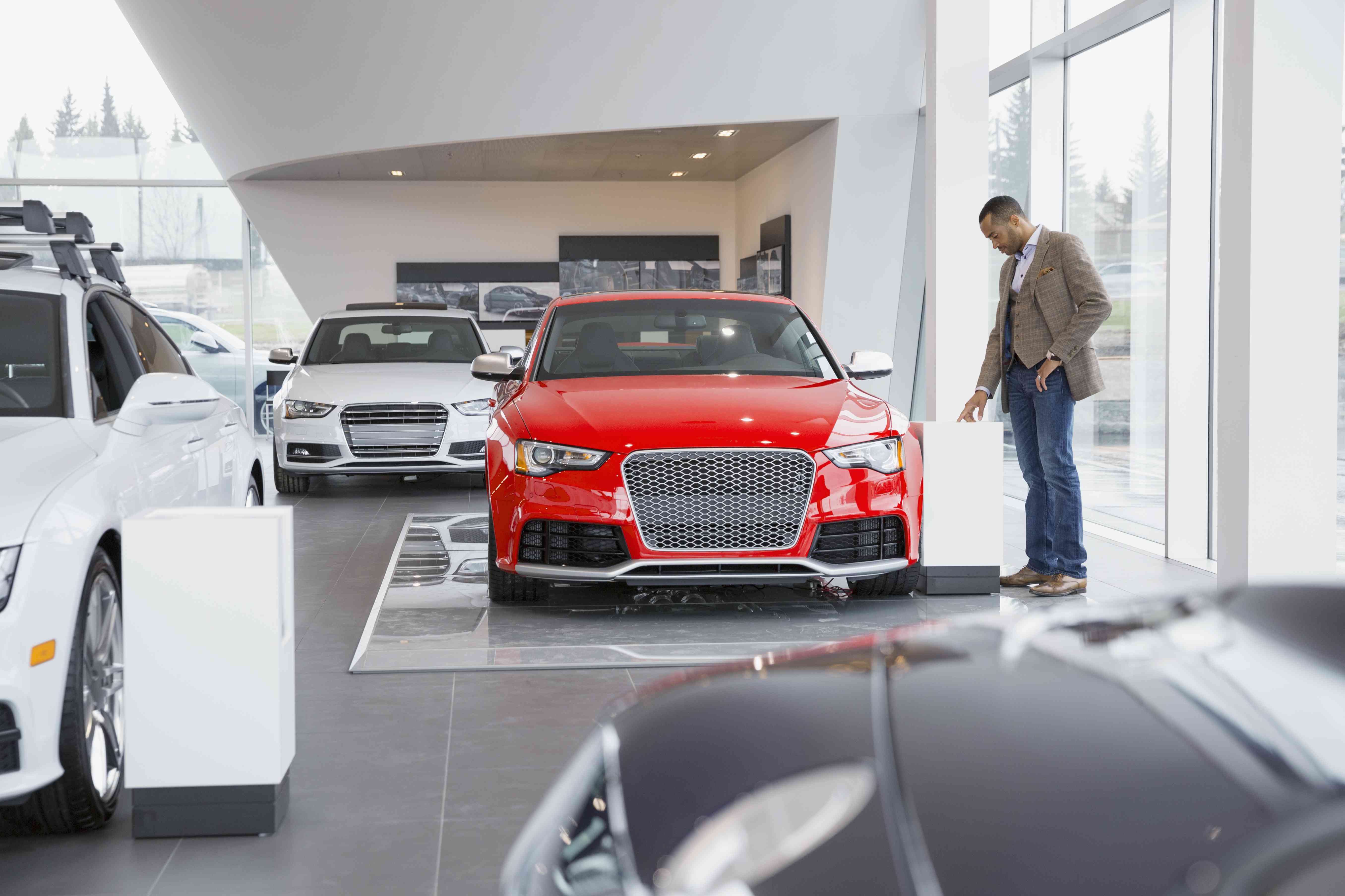 Man looking at car in car dealership showroom