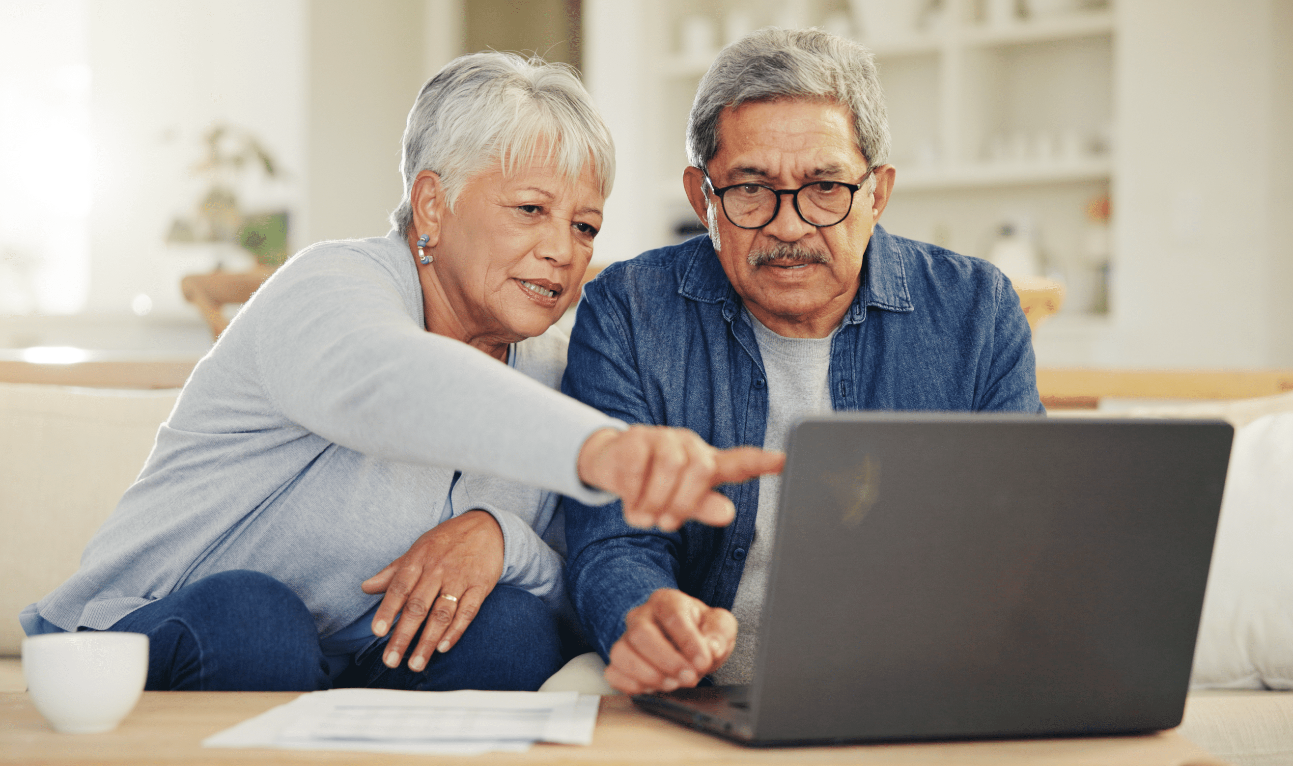 Older couple looking together at a laptop in their living room