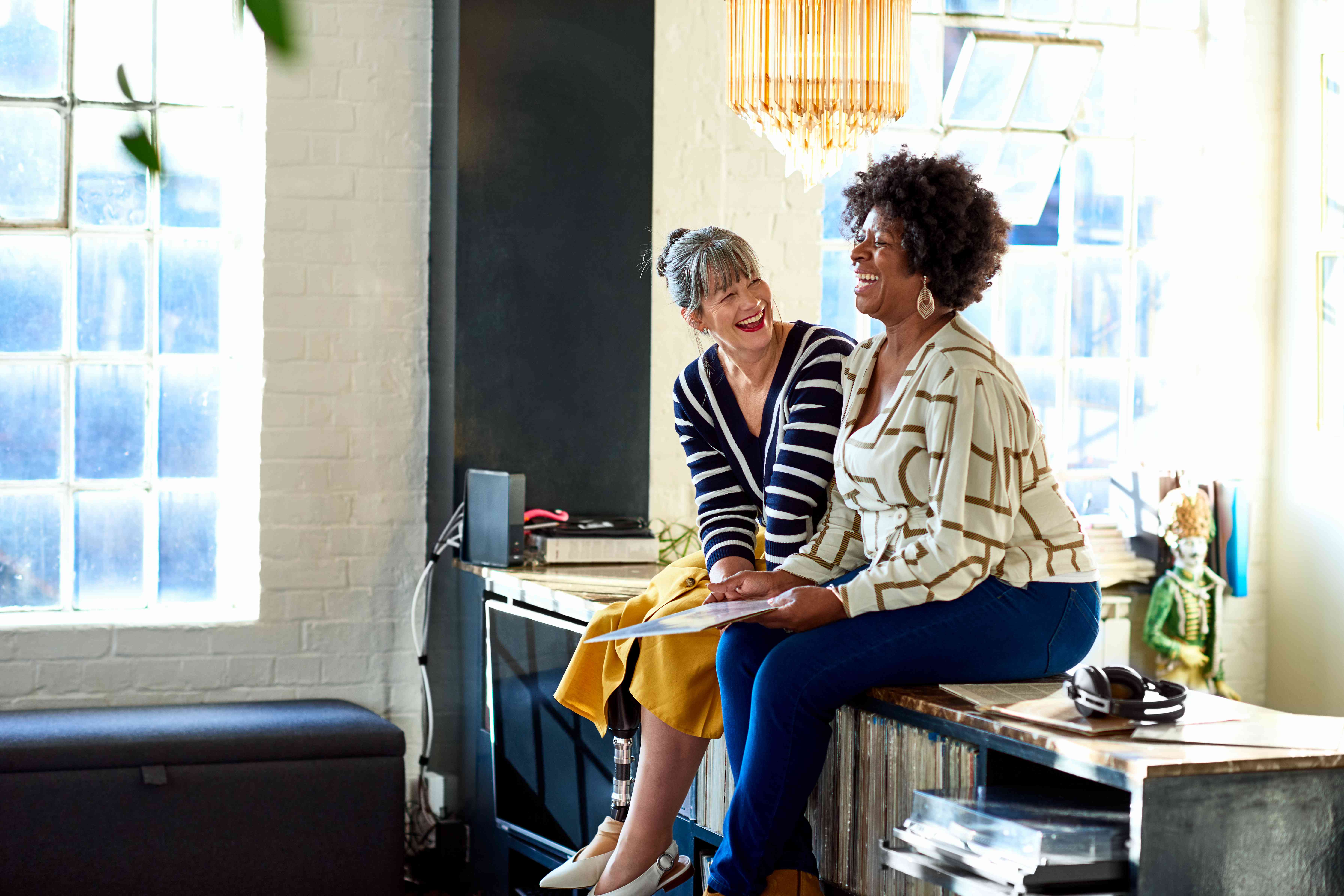 Two friends sitting on a sideboard smiling.