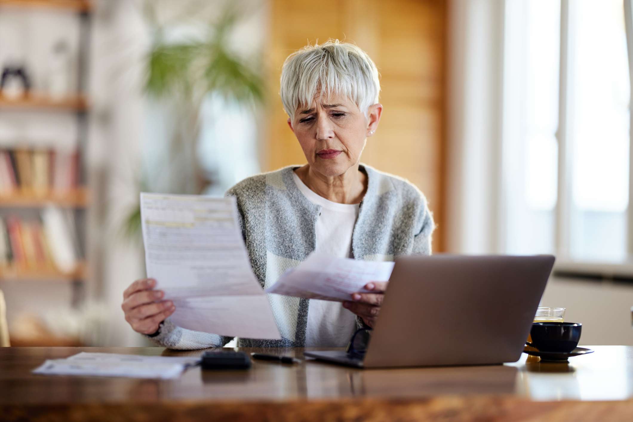 A woman reviews documents at a desk.