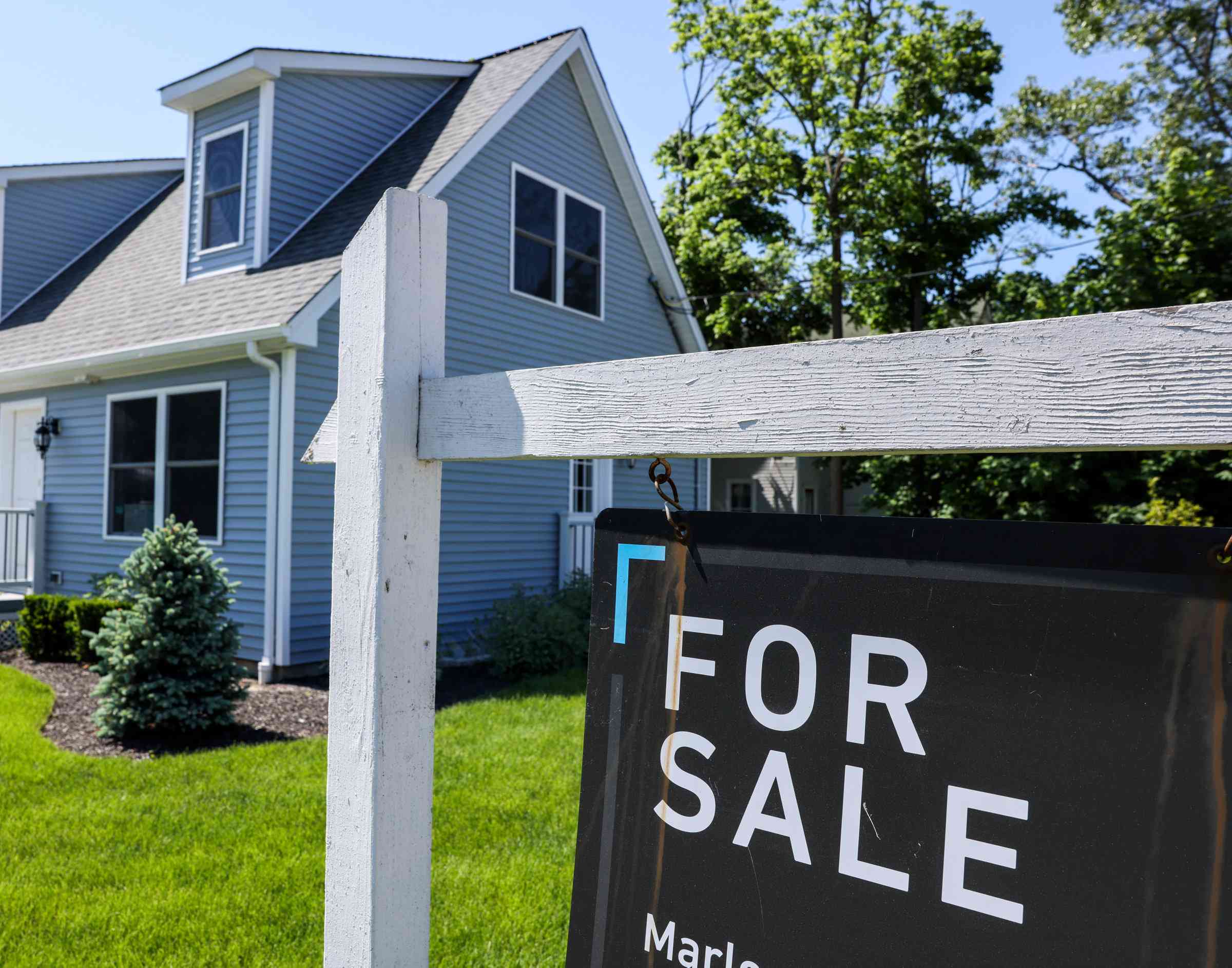 For Sale sign hangs in front of a house in Patchogue, New York