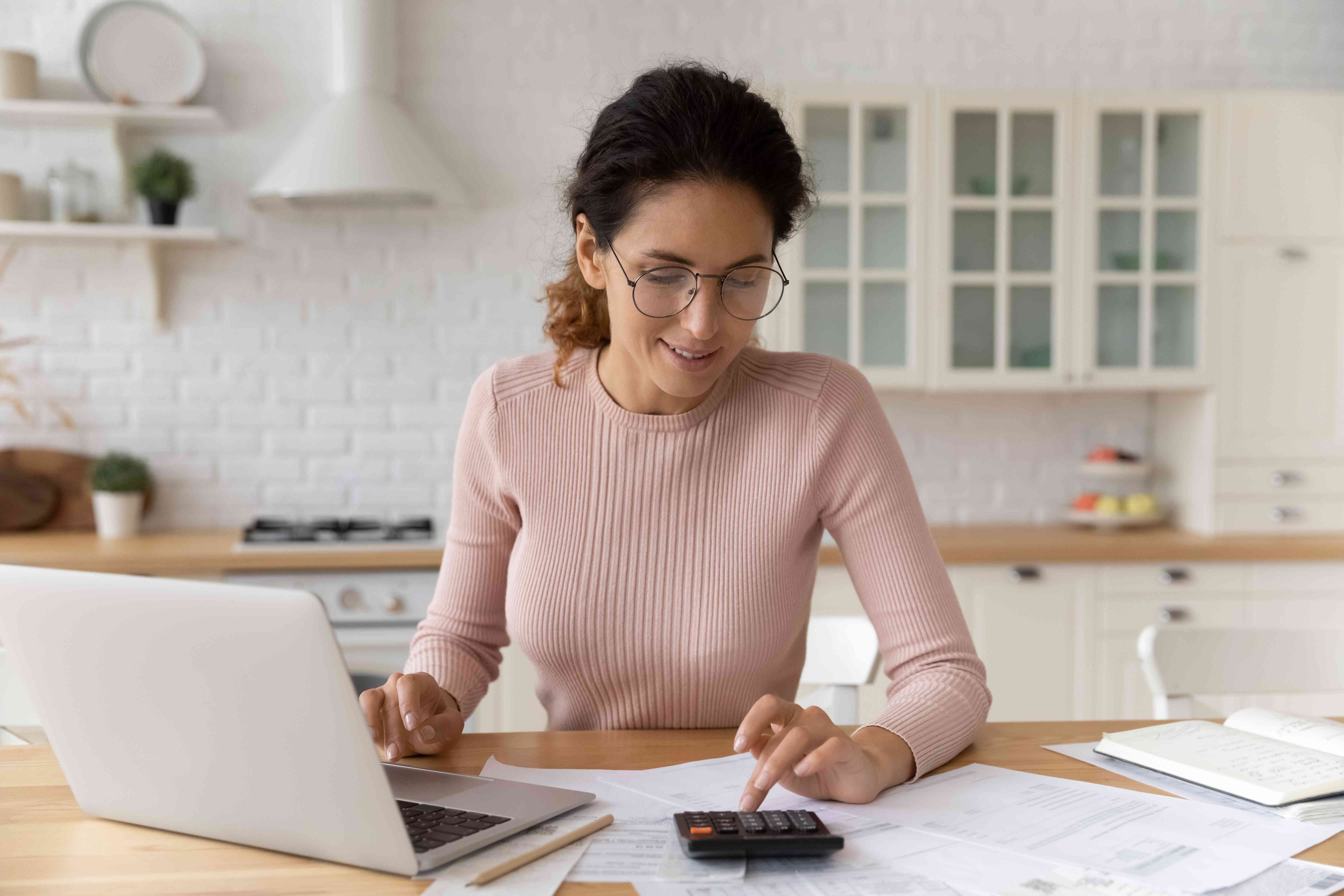 Woman using a calculator and computer while doing paperwork