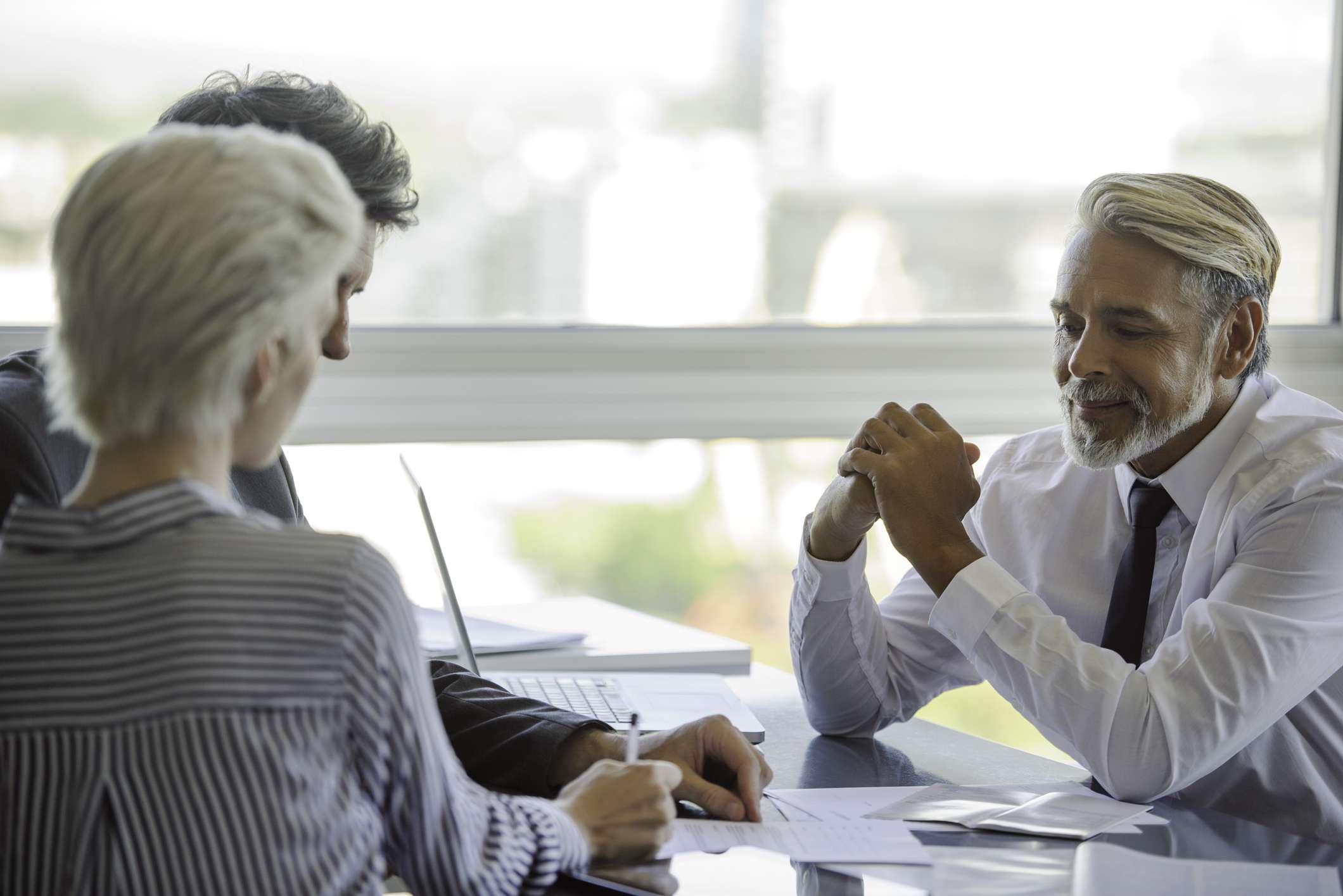 A couple with a financial advisor signing a document.