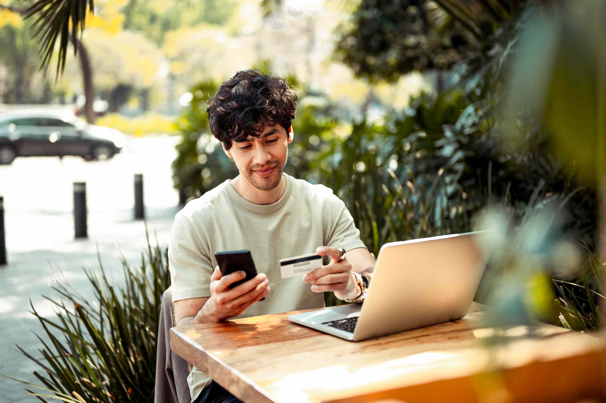 A man sits at a table with a laptop using a credit card.