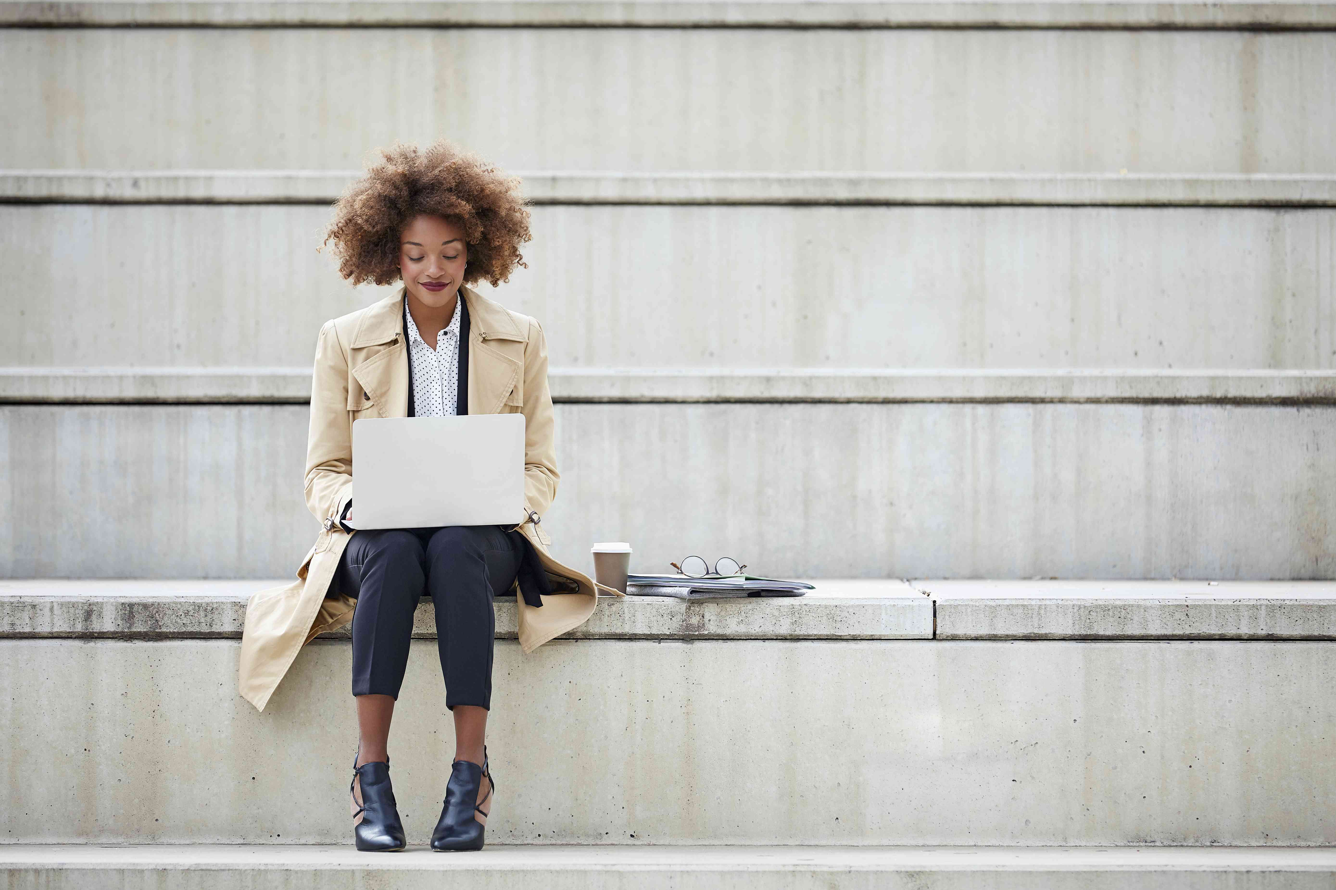 Young businessperson using laptop while sitting on steps. 