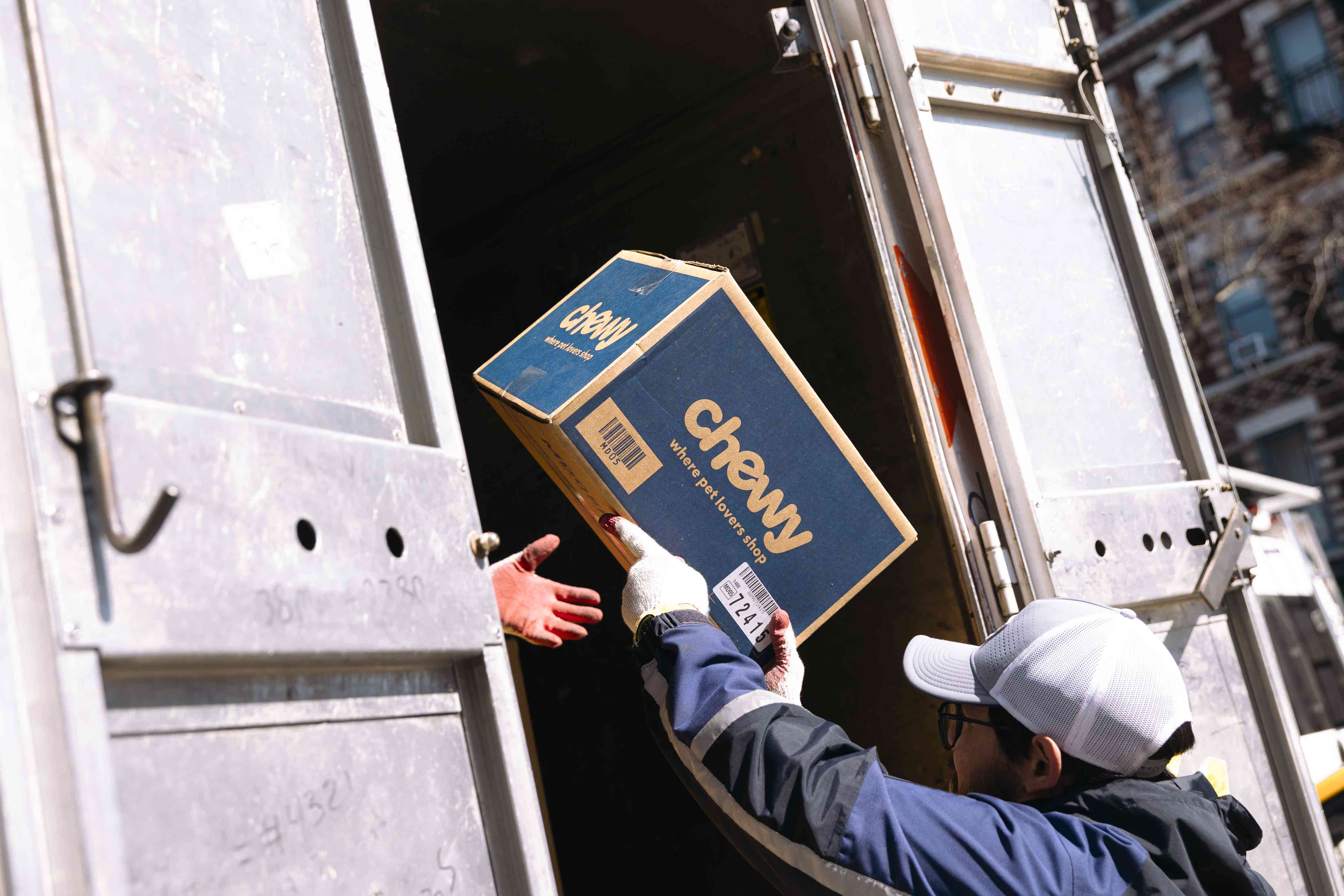 A worder unloads a Chewy box from a delivery vehicle in New York City. 