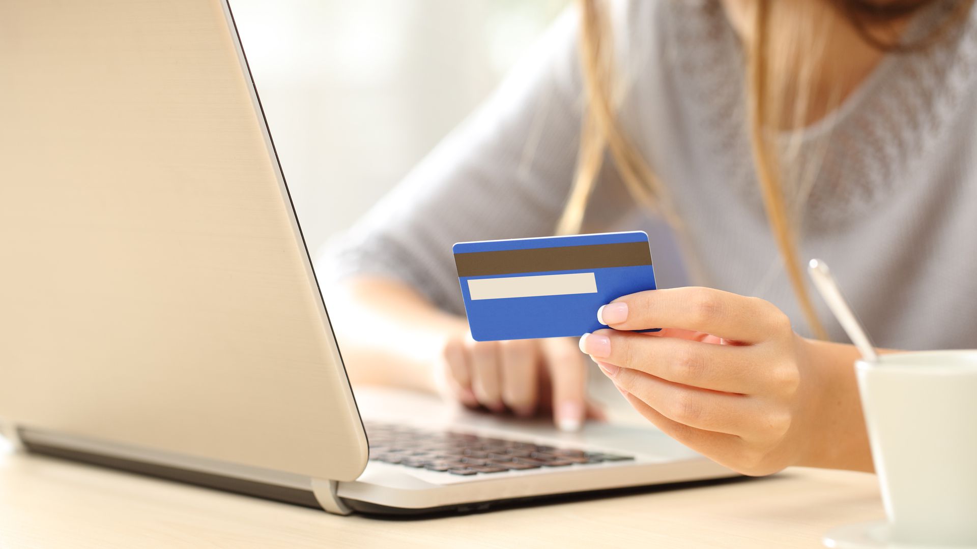 A woman signing up for a YouTube Membership with her credit card and laptop.