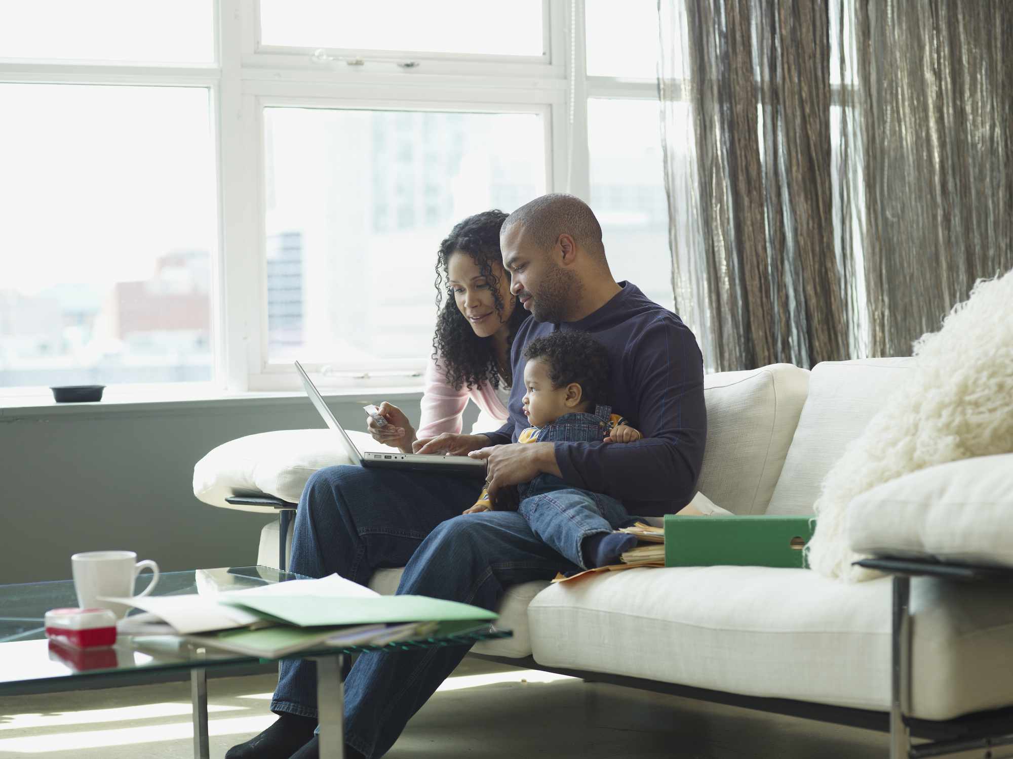 Couple with baby on a sofa looking at a laptop