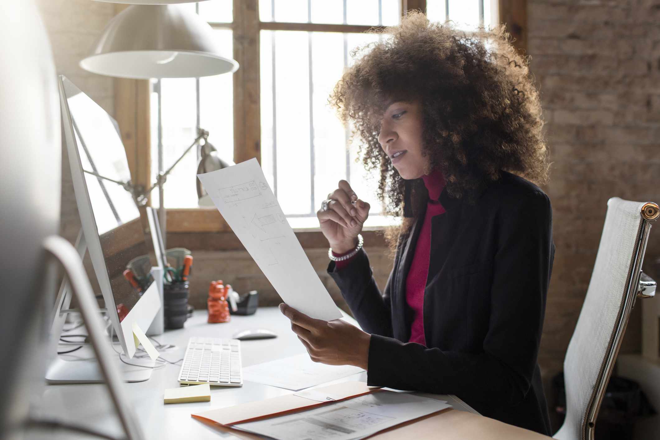 A woman reviews documents at a desk.