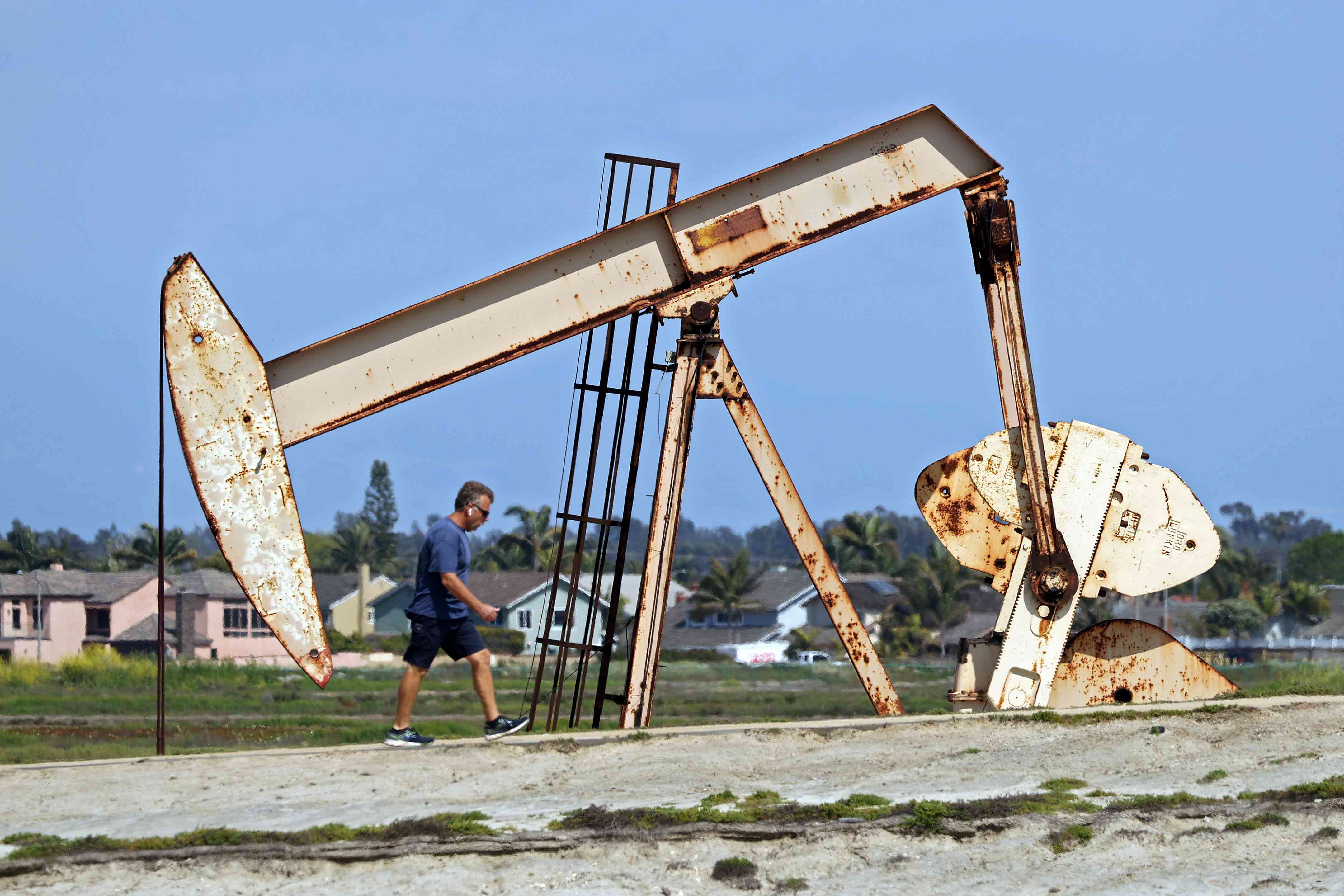 Man walking in front of an oil derrick