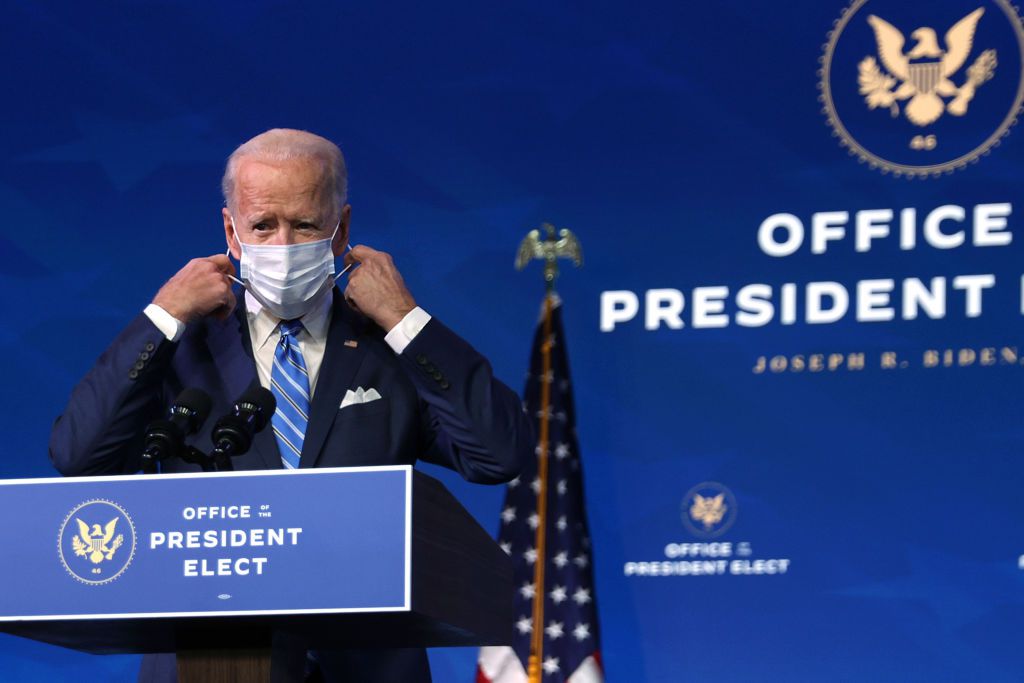 Joe Biden at podium putting on mask