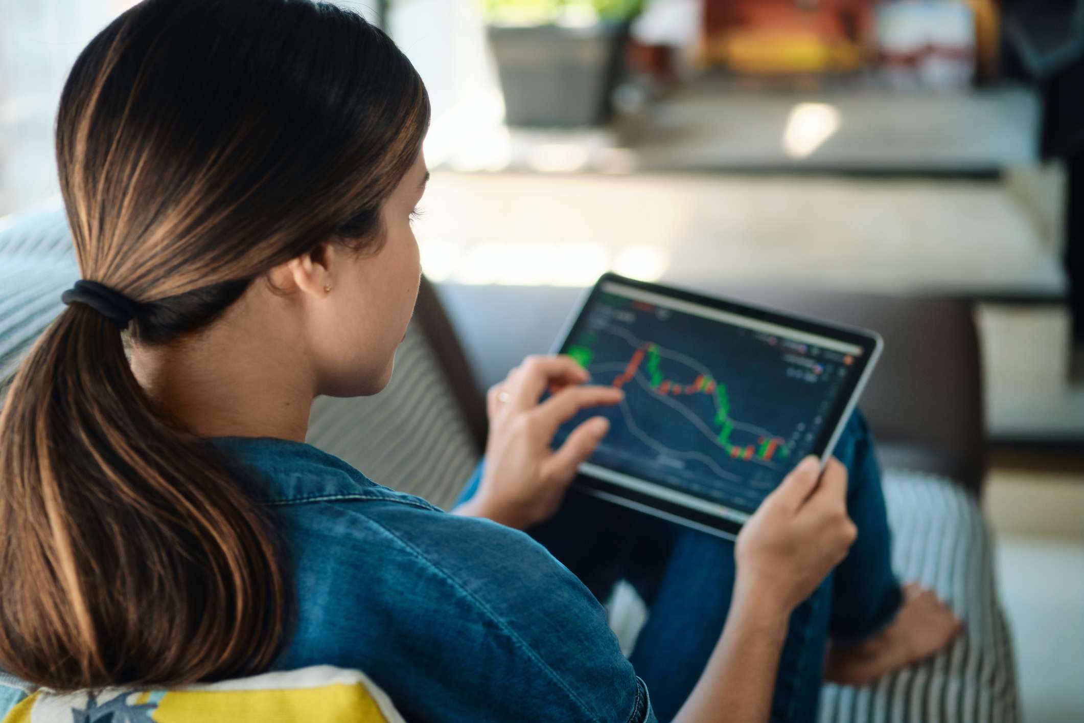 Person on sofa at home, trading online with tablet