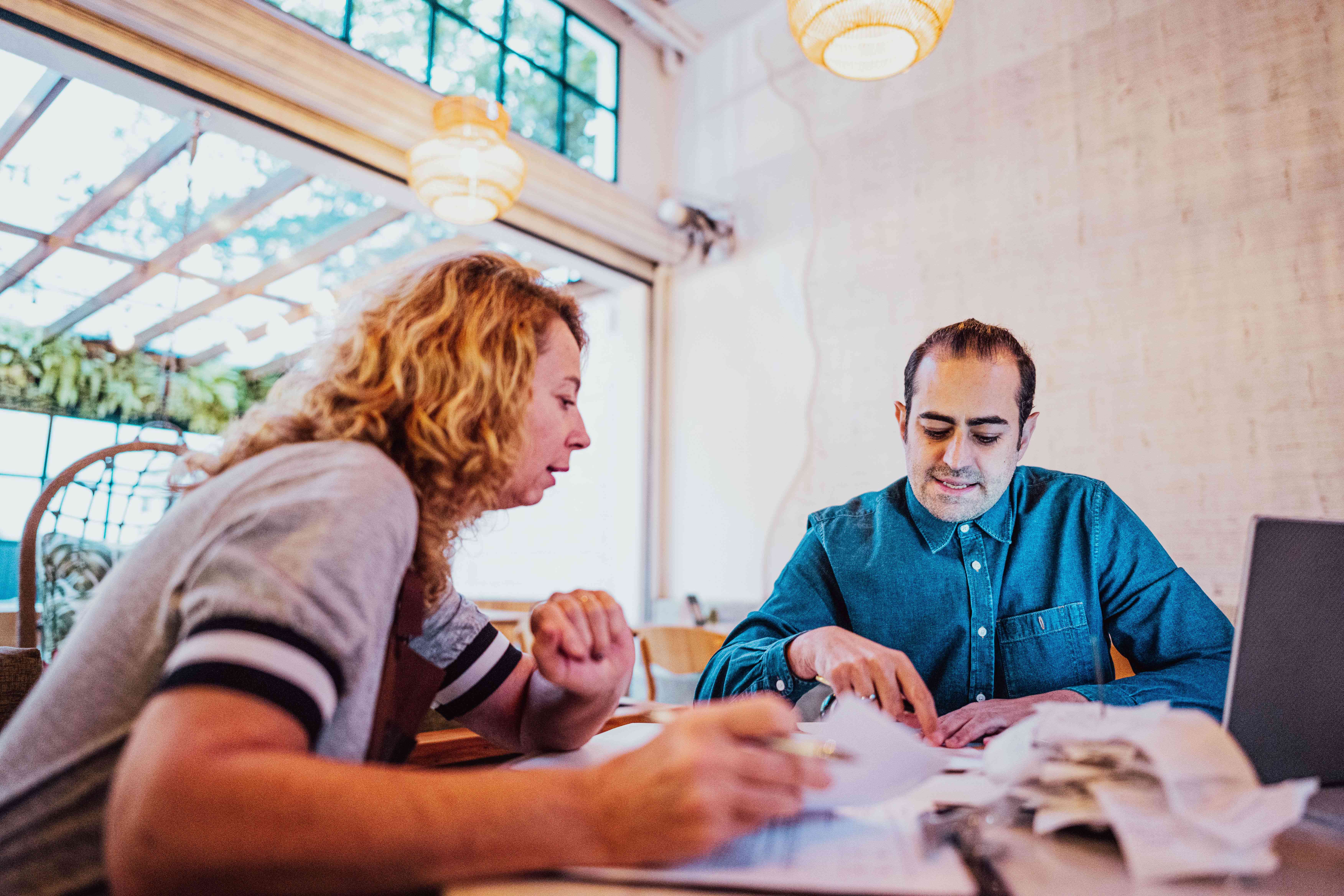 Two people doing paperwork at a coffee shop