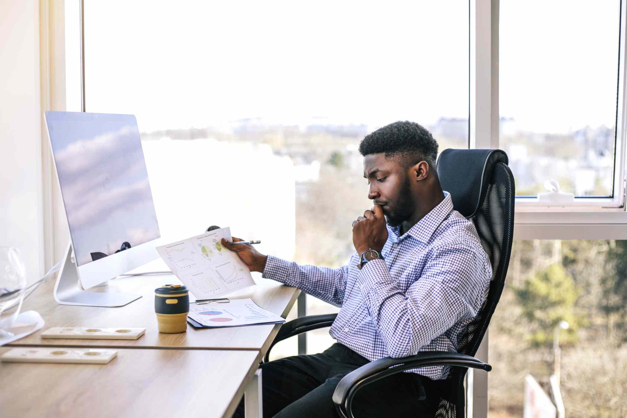 A man sits at his desk reviewing investment paperwork