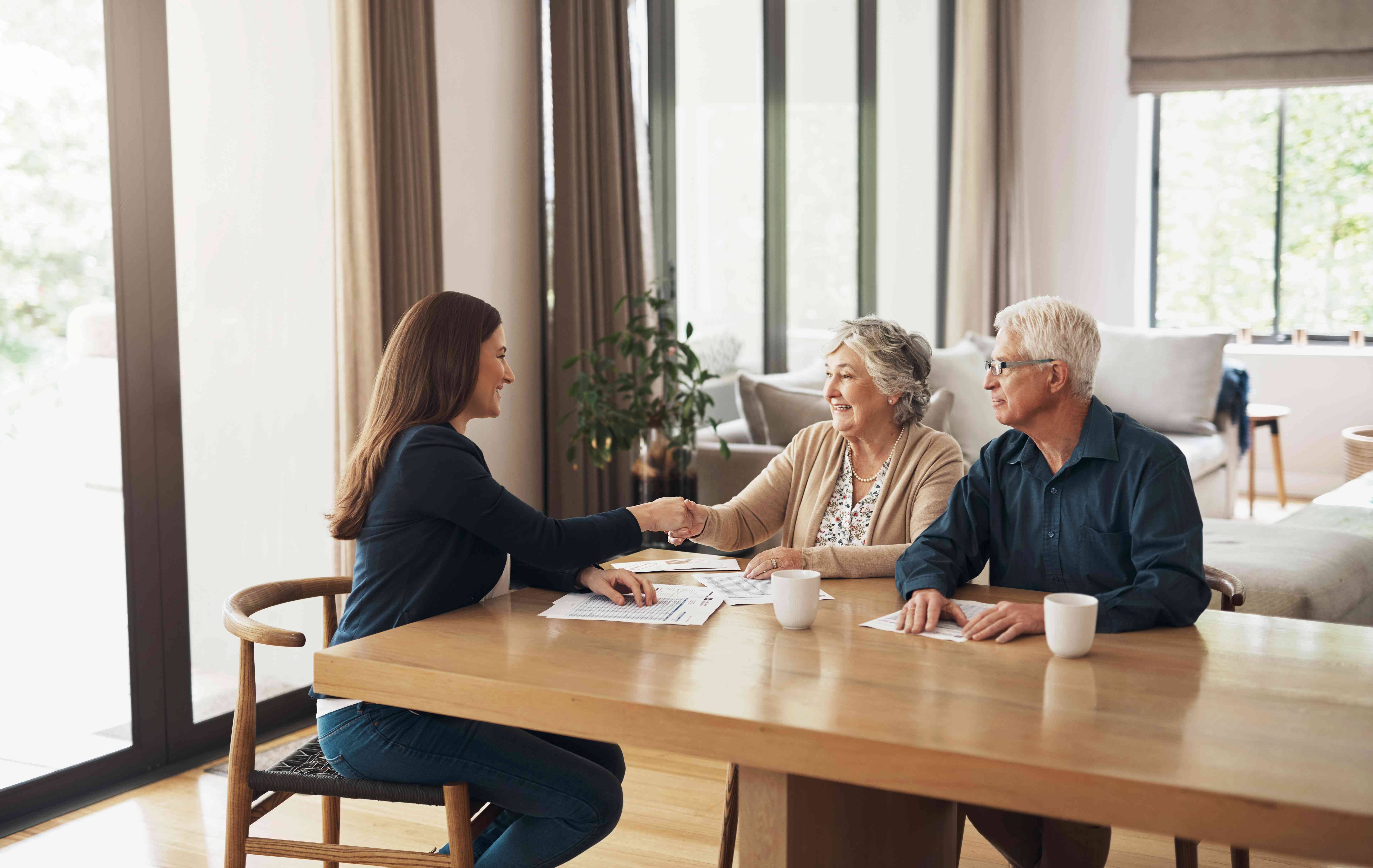 Financial advisor shaking hands with a couple she is advising.