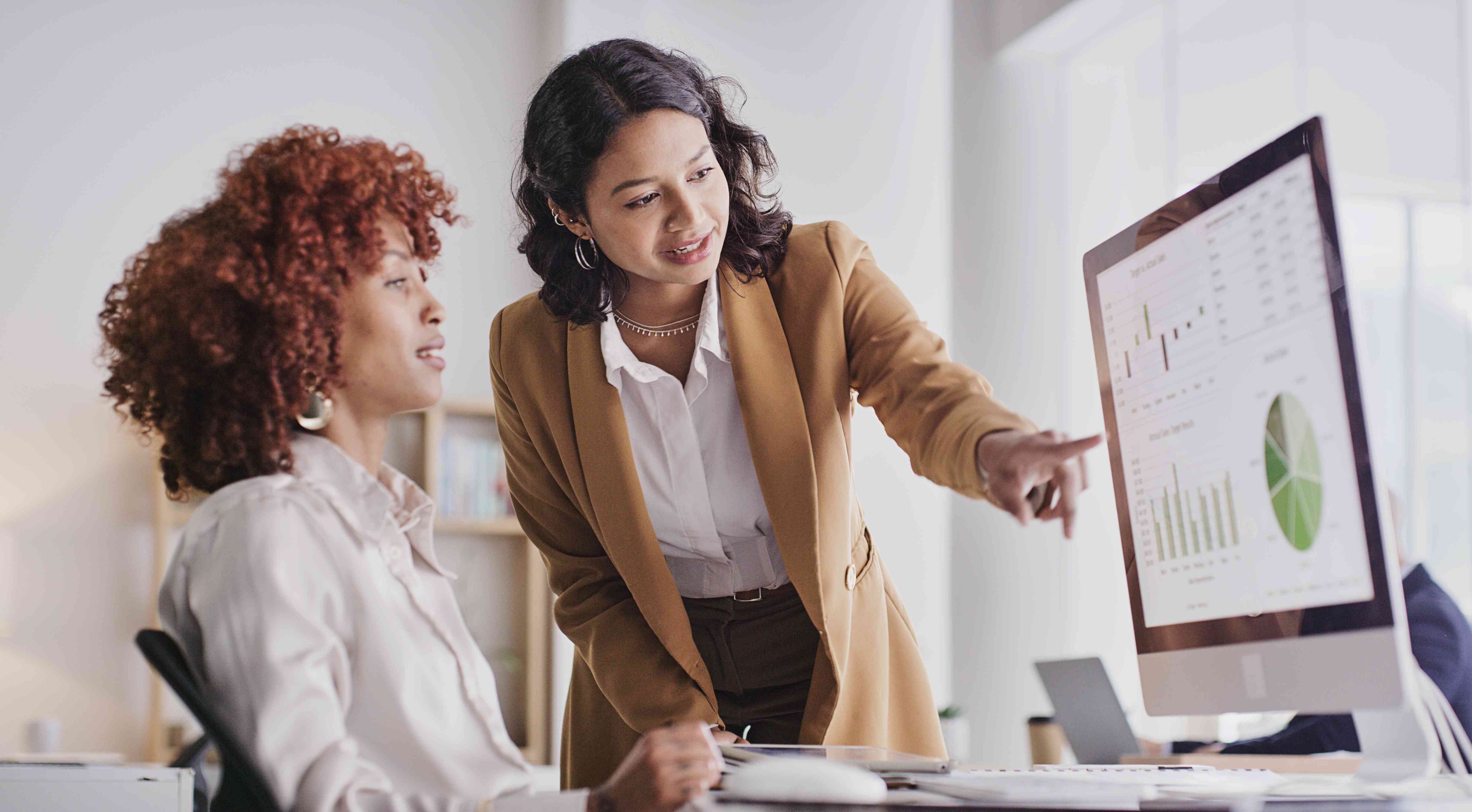  Two people in collaboration looking at company data or analysis on PC