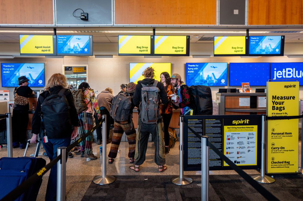 Customers wait in line to drop baggage off at a Spirit Airlines check-in counter at the Austin-Bergstrom International Airport on April 10, 2024 in Austin, Texas.