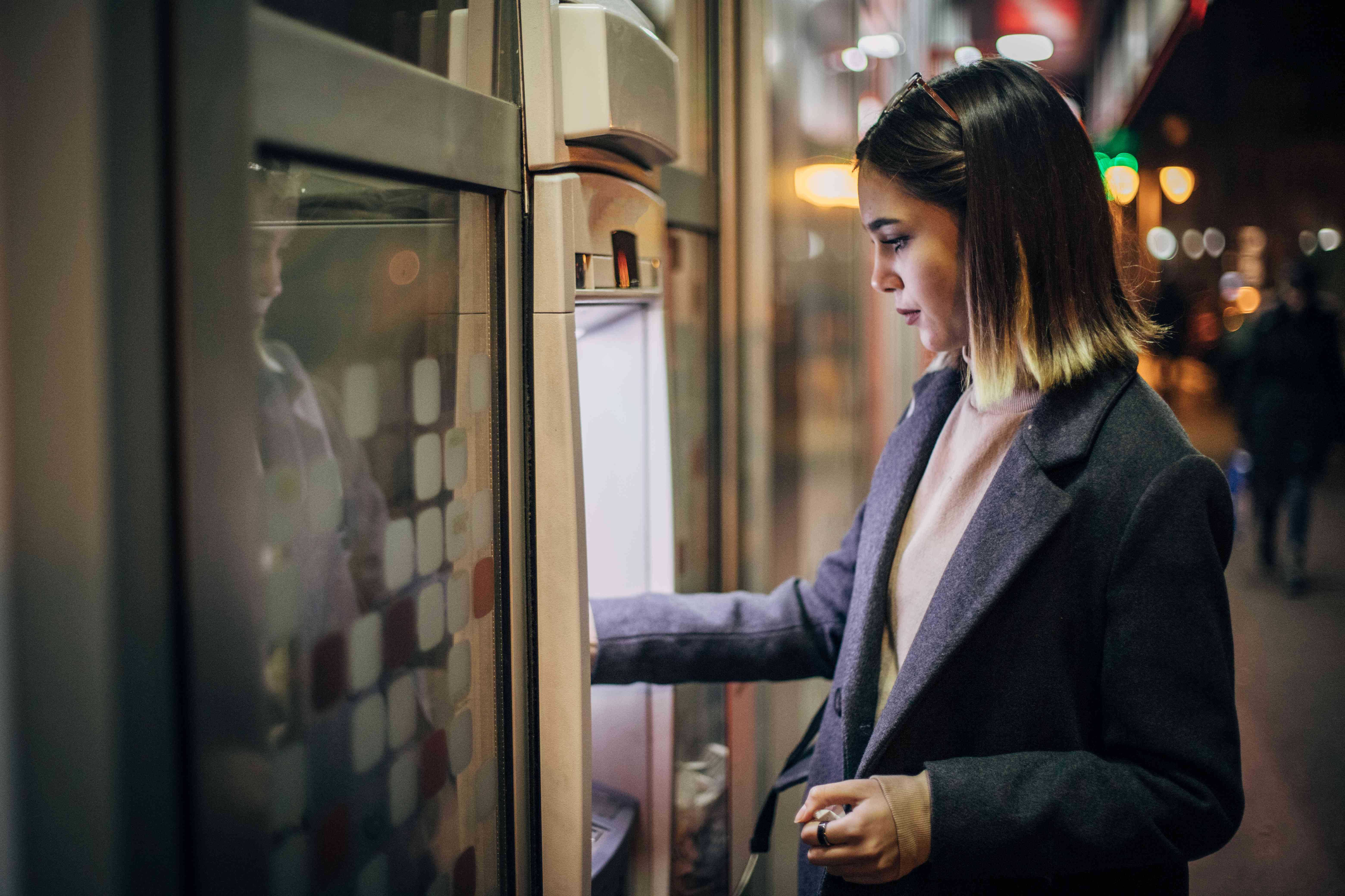 Young woman making bank deposit at ATM machine.