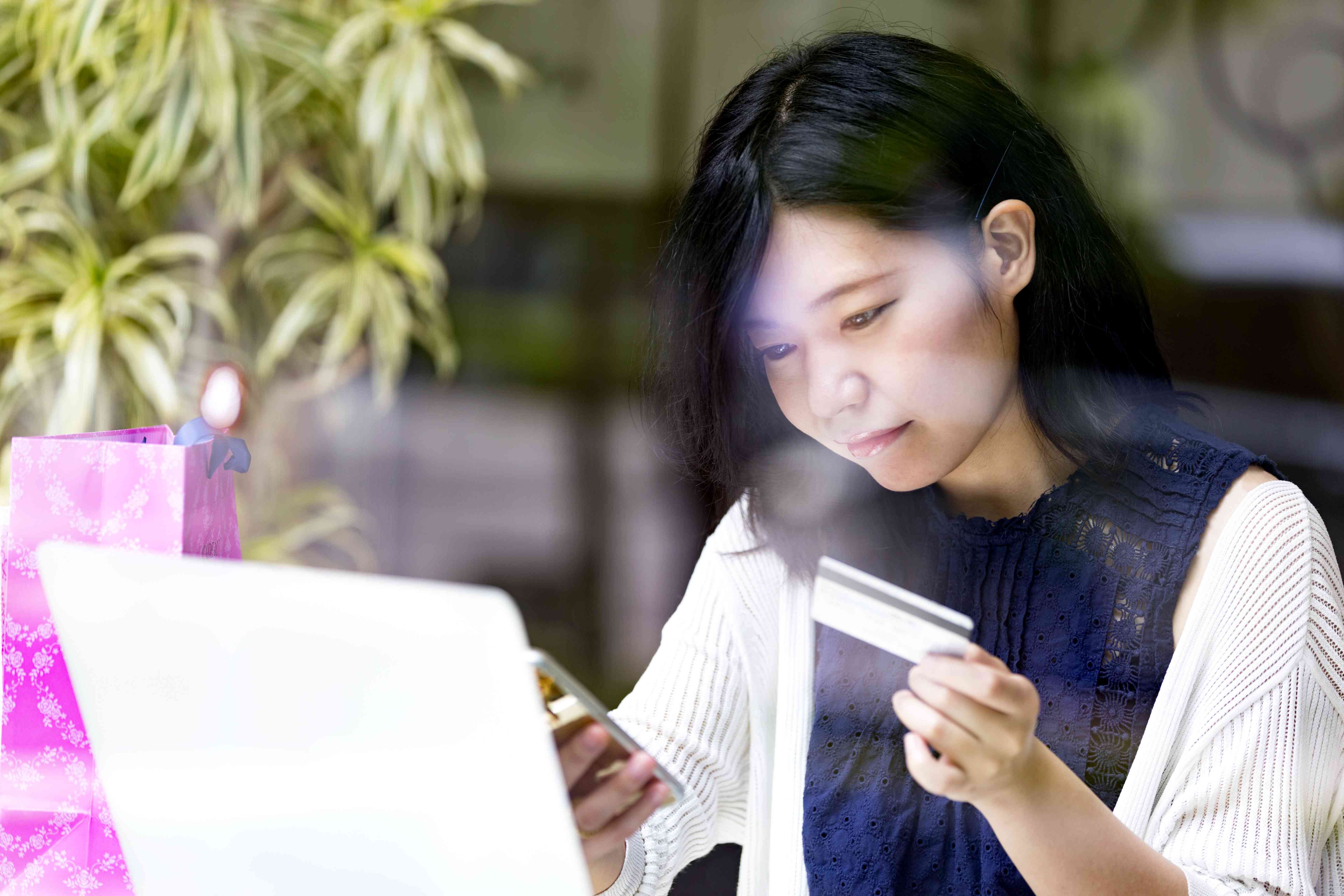 Japanese girl using her smartphone and credit card to make an online payment