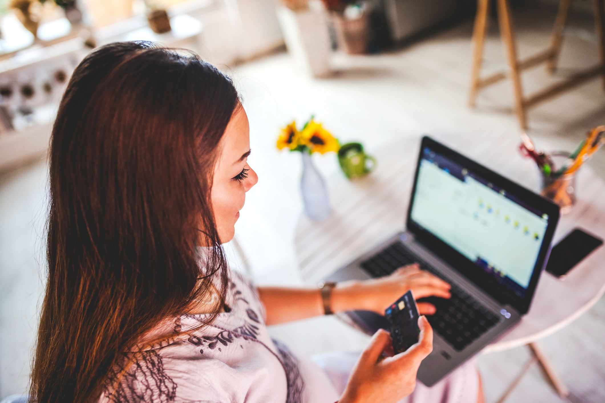 Young woman paying bills with credit card at her laptop at home.