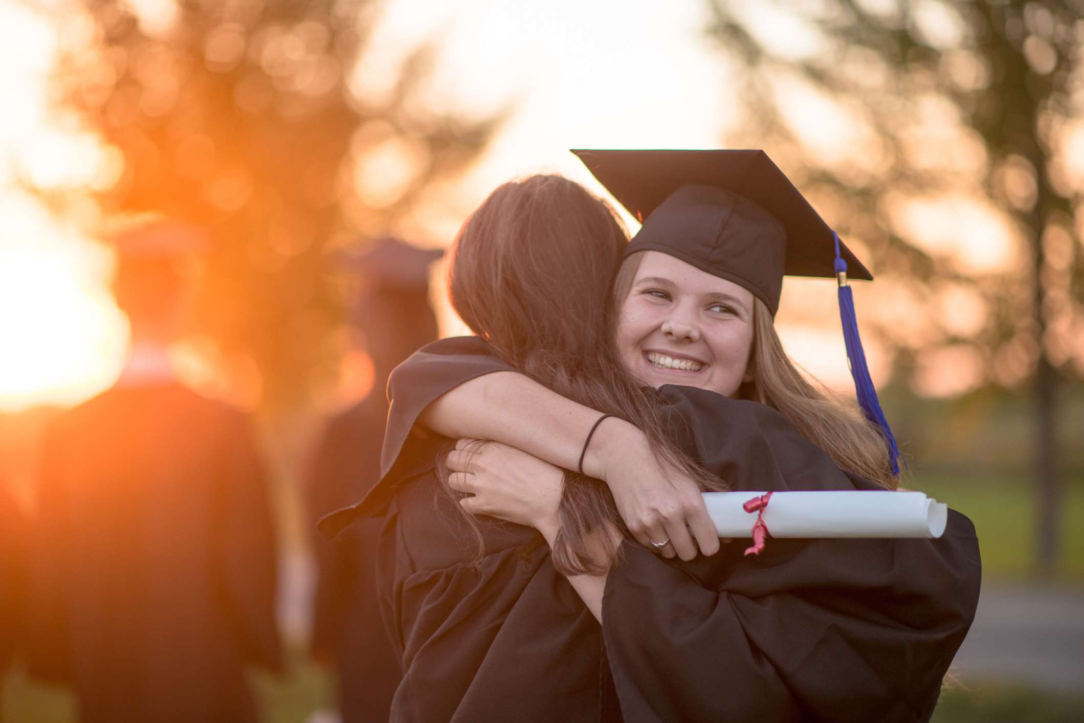 A college graduate hugs someone.