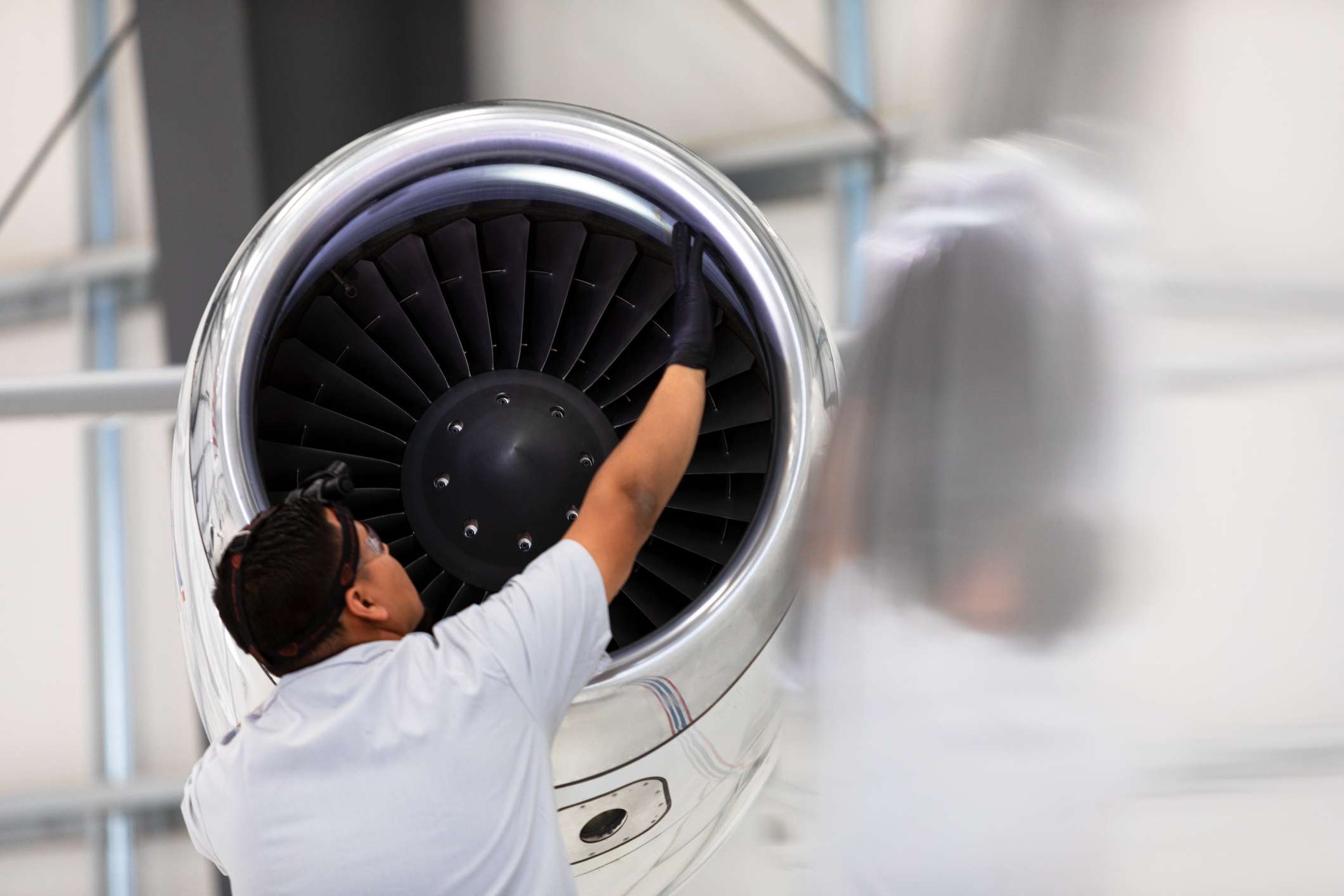 An airplane mechanic checking the jet engine while working on a private jet inside the hangar of a small general aviation airport in California.