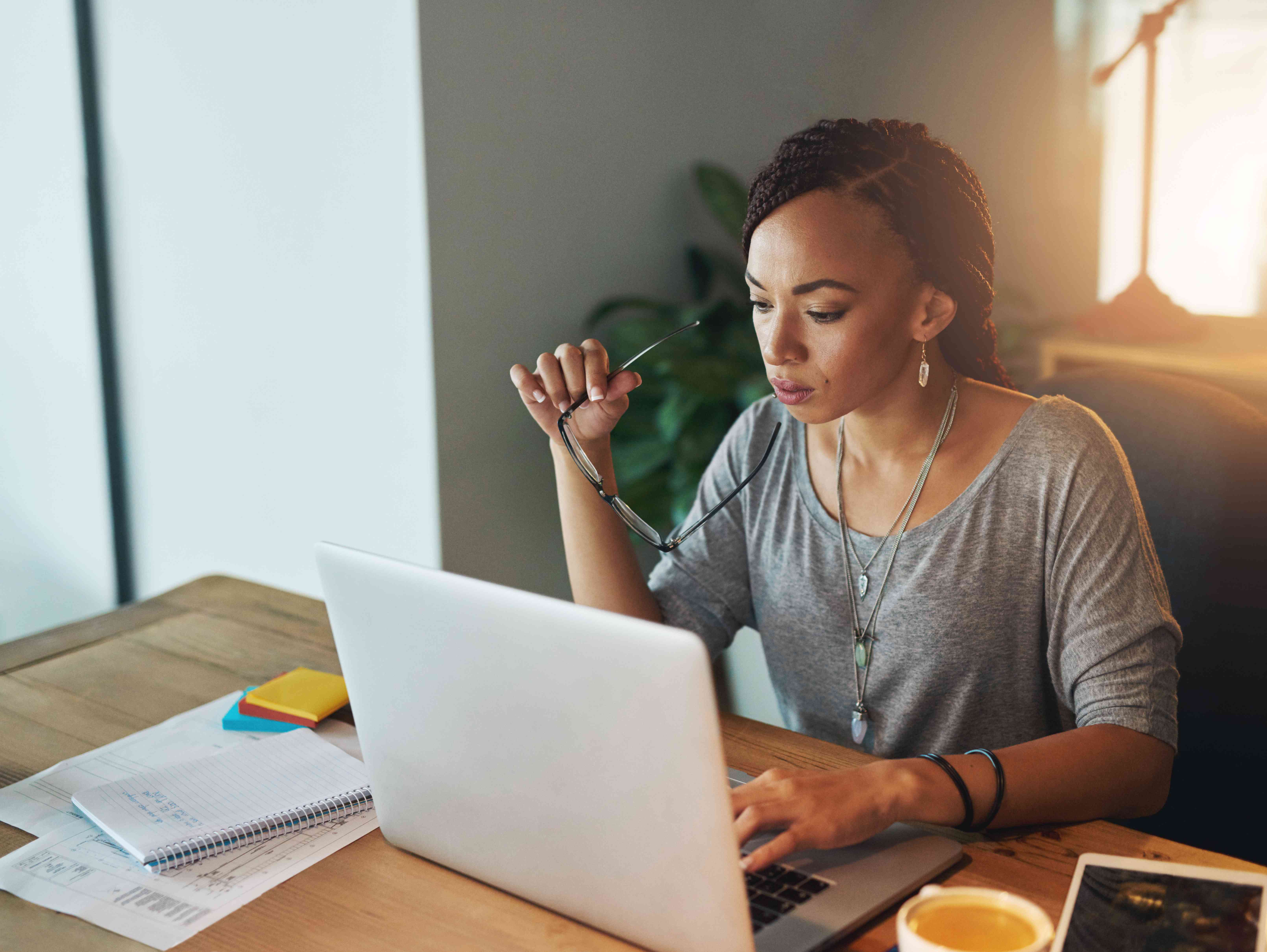 A woman sits at a desk with a laptop while applying for a private mortgage.