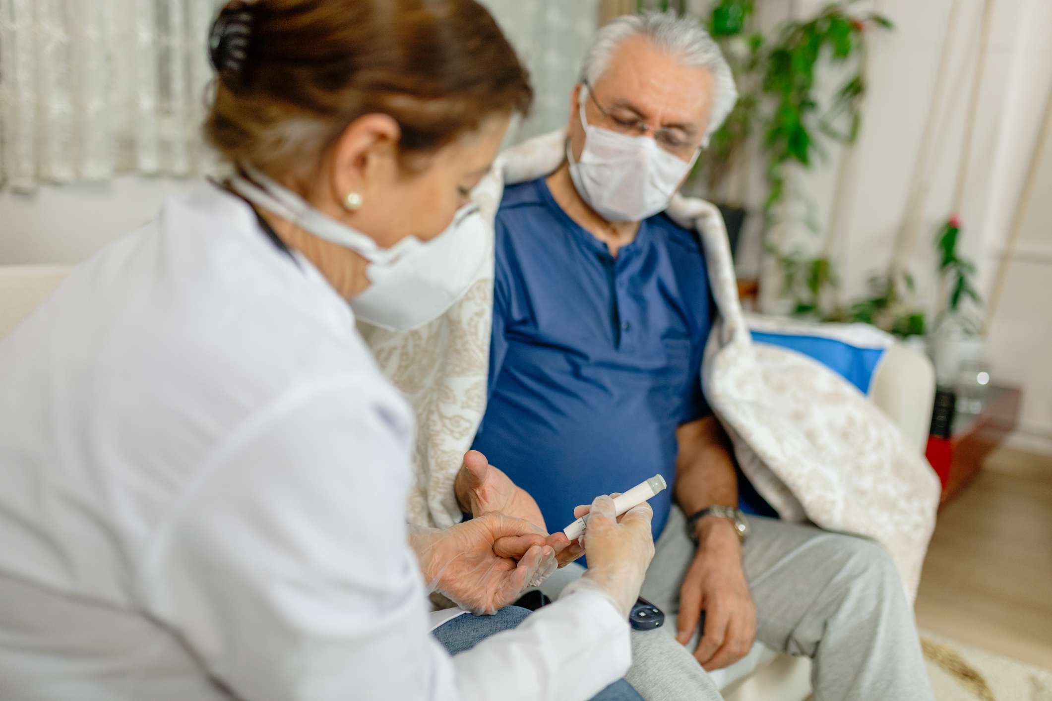 Man getting blood glucose testing by home health nurse during COVID-19 pandemic