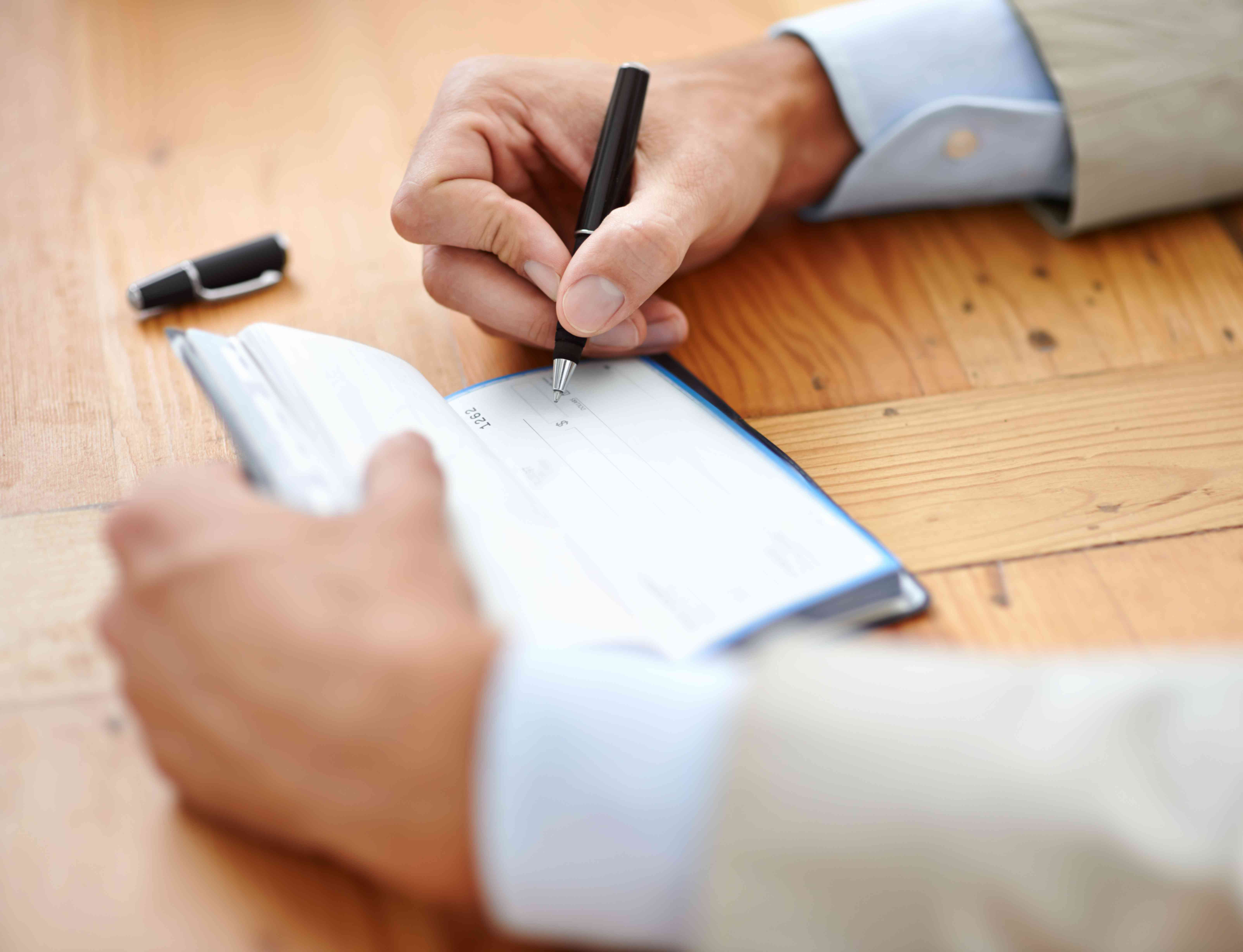 A man in a suit fills out a check in a check book