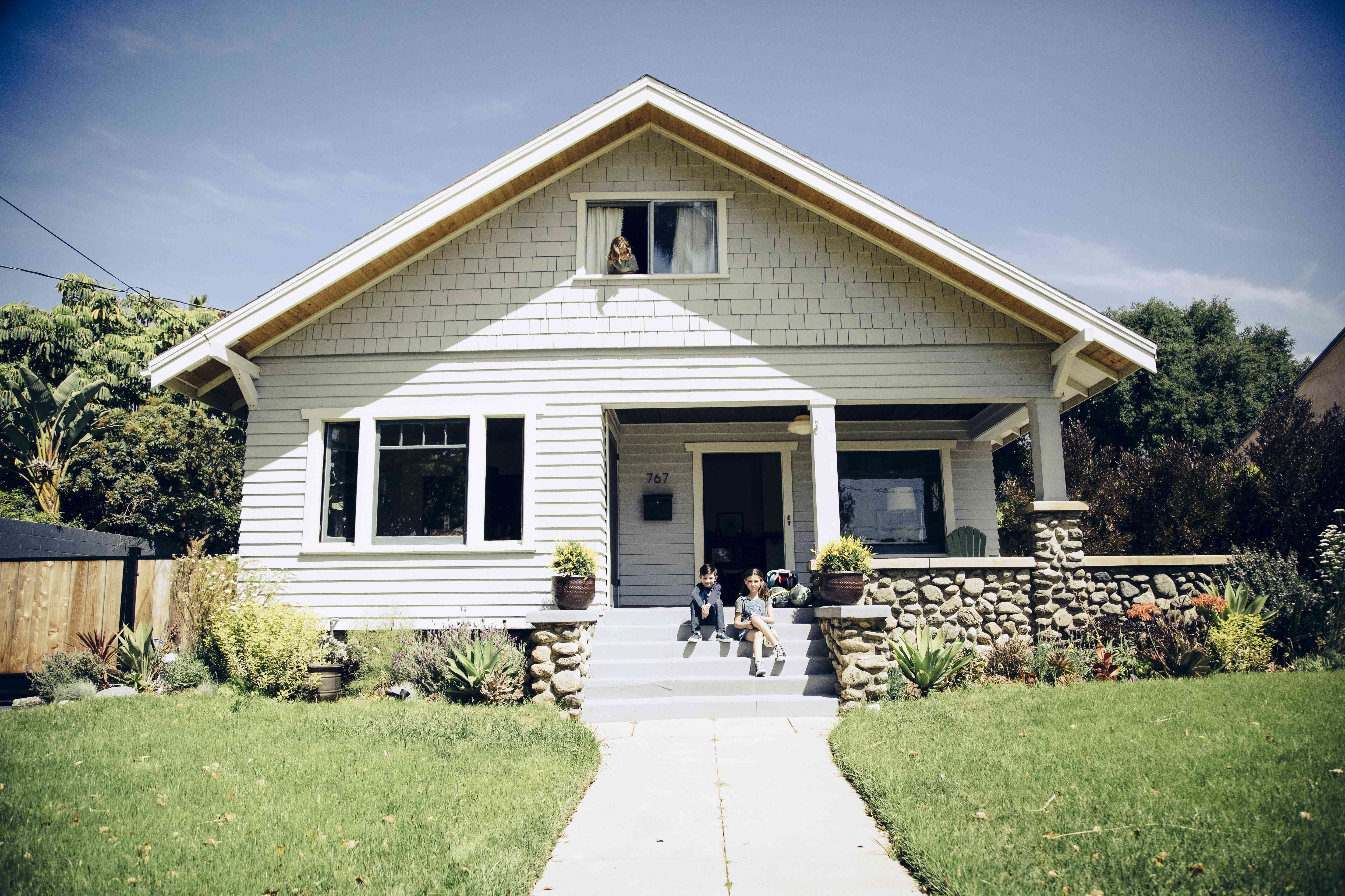 a boy and a girl sit on the front steps of a house